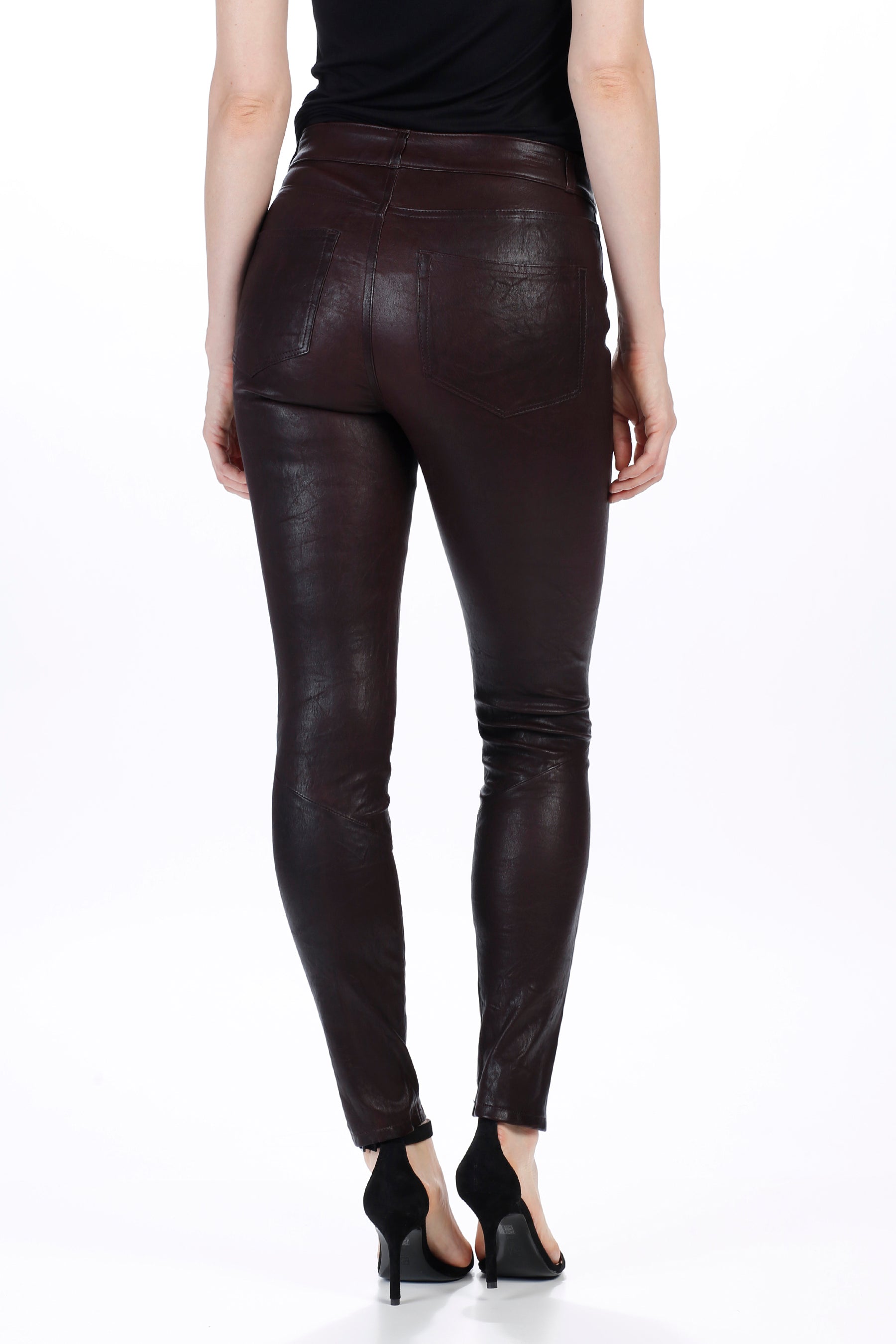 Person wearing dark brown leather leggings on a white background