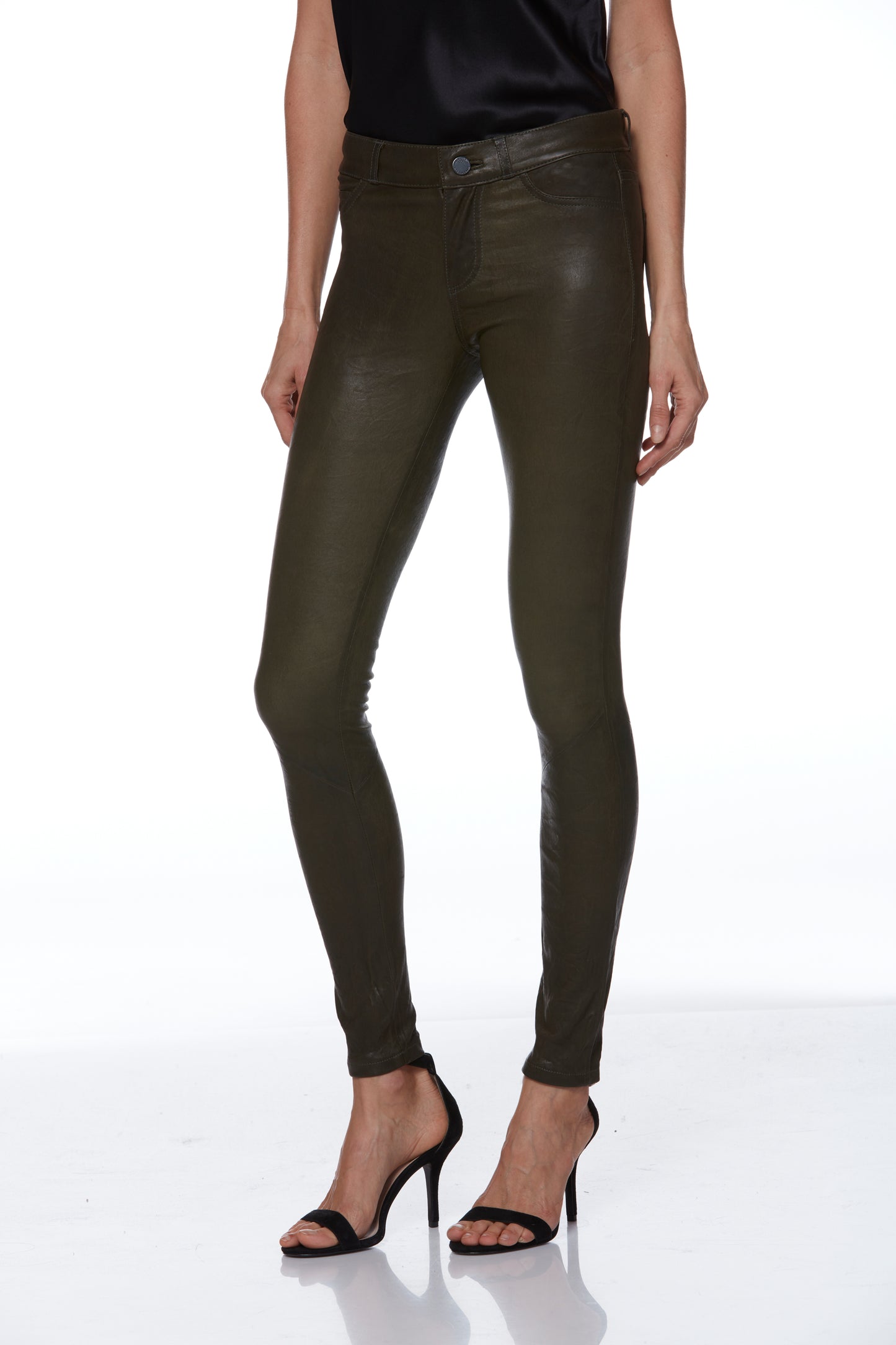 Person wearing olive green leather pants on a white background