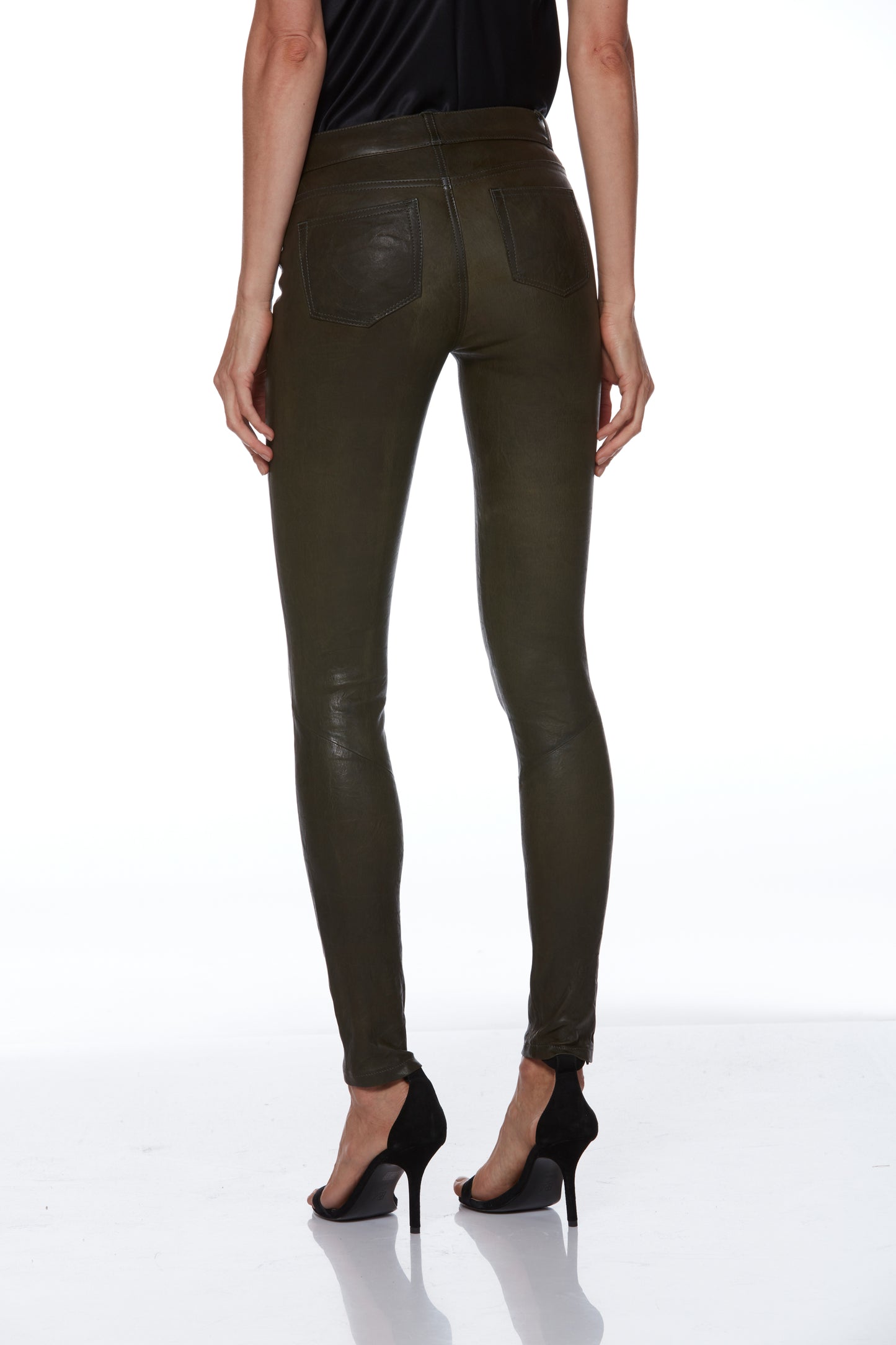 Person wearing olive green leather pants on a white background