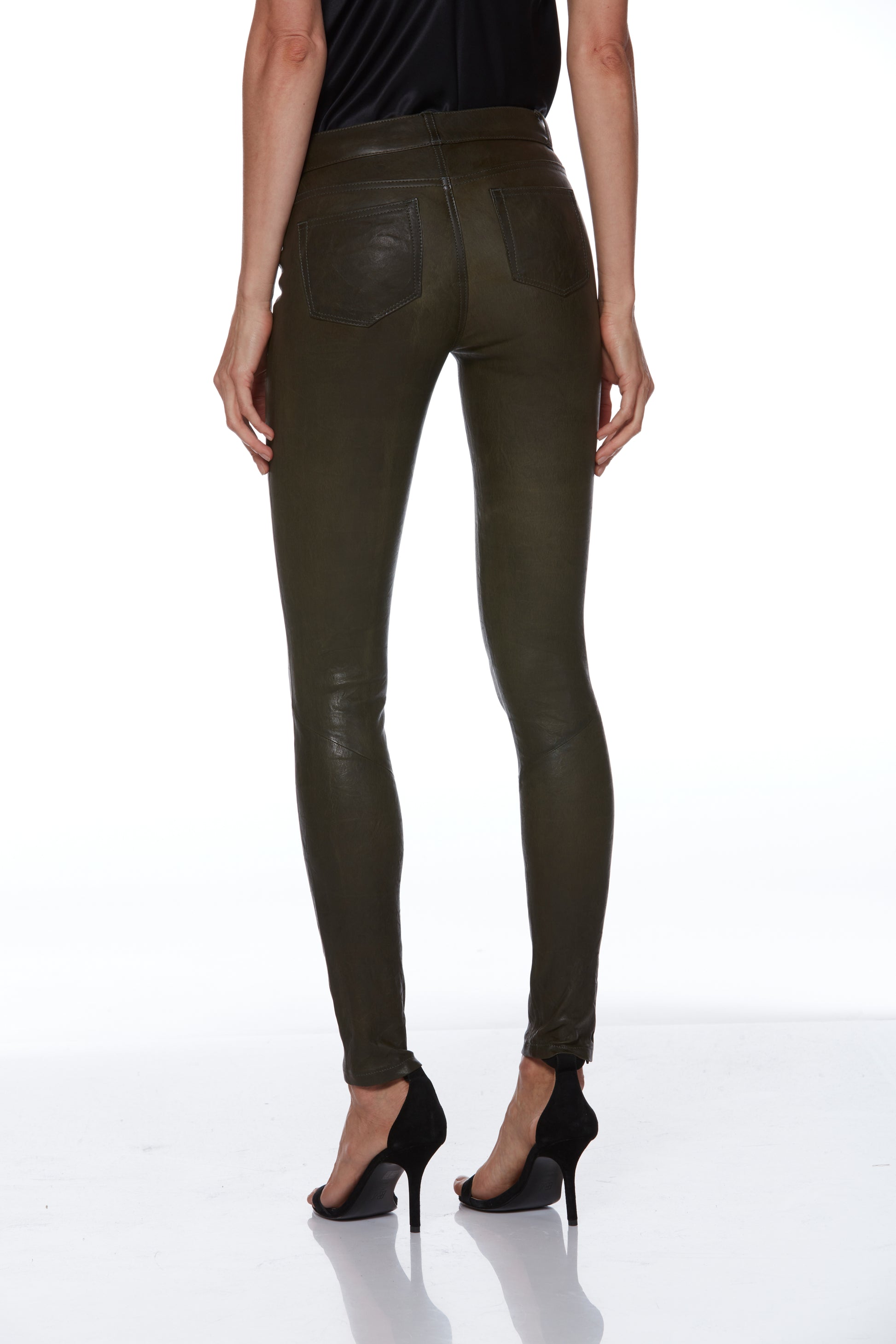 Person wearing olive green leather pants on a white background