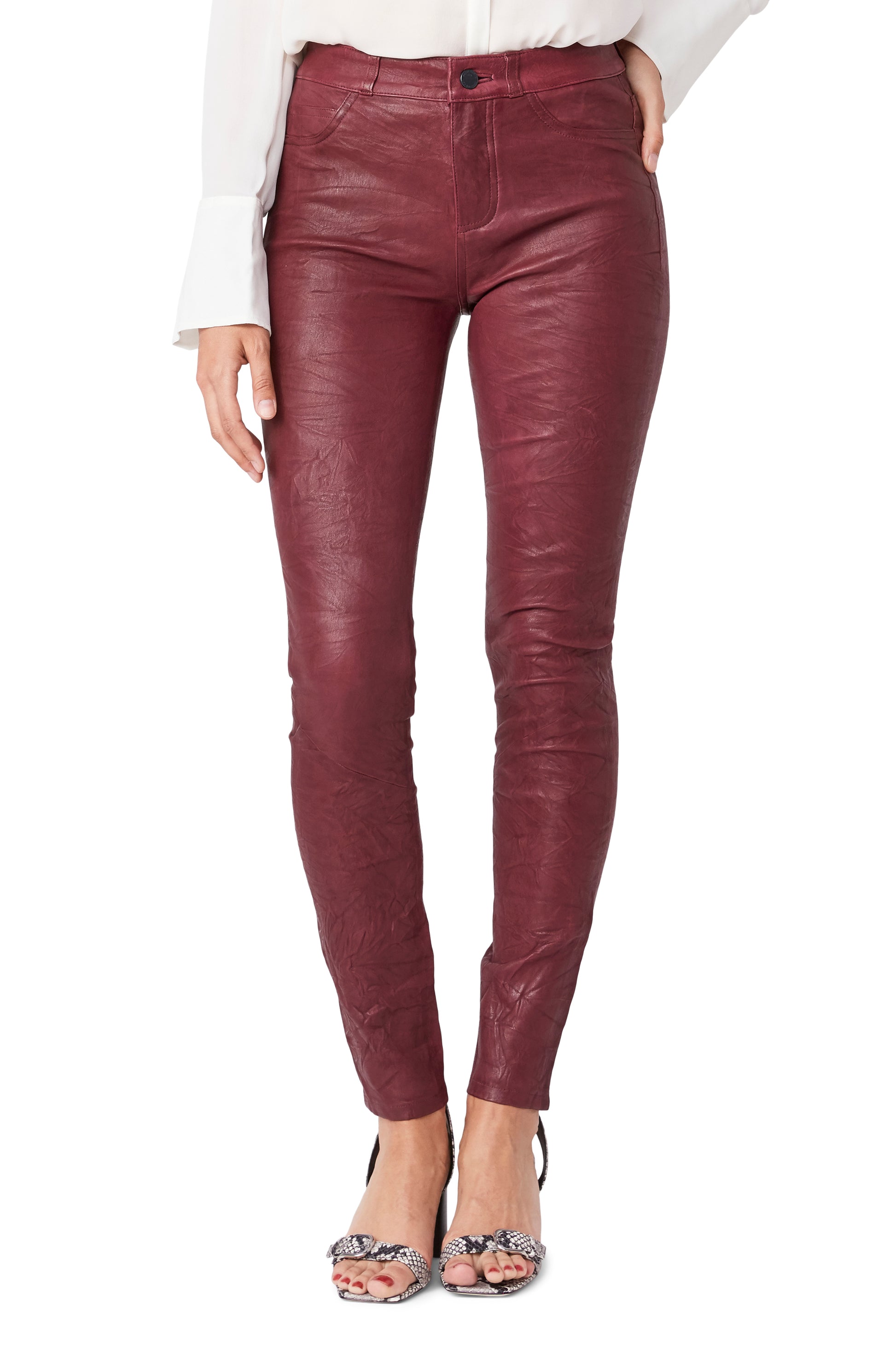 Burgundy leather pants worn by a person on a white background