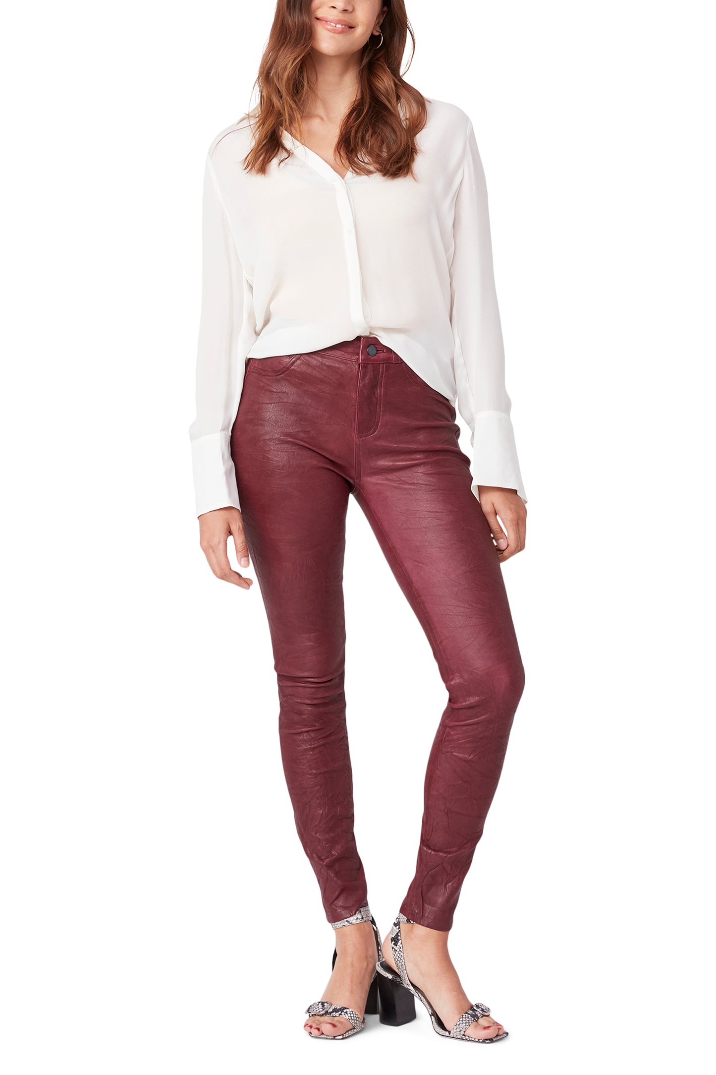 Woman wearing a white blouse and maroon leather pants on a white background