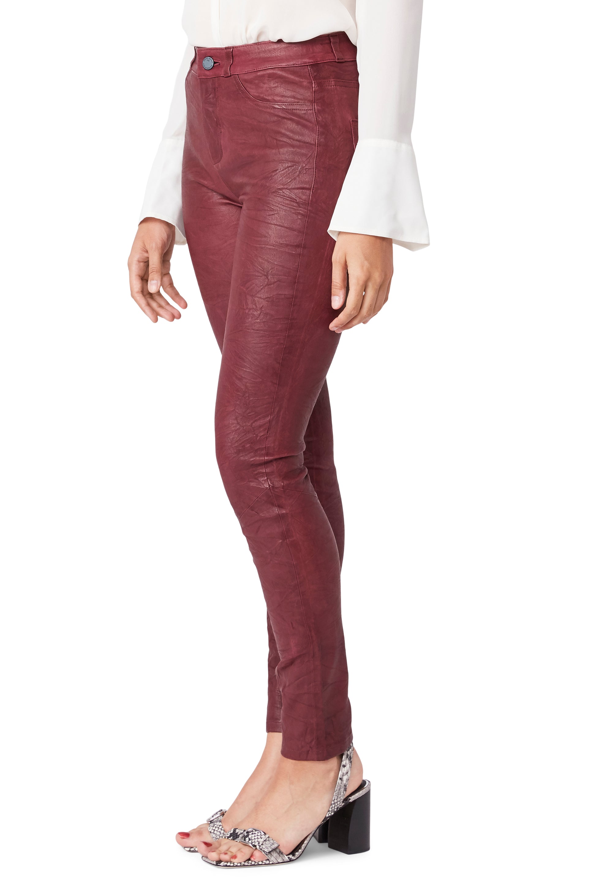 Maroon leather pants worn by a person on a white background