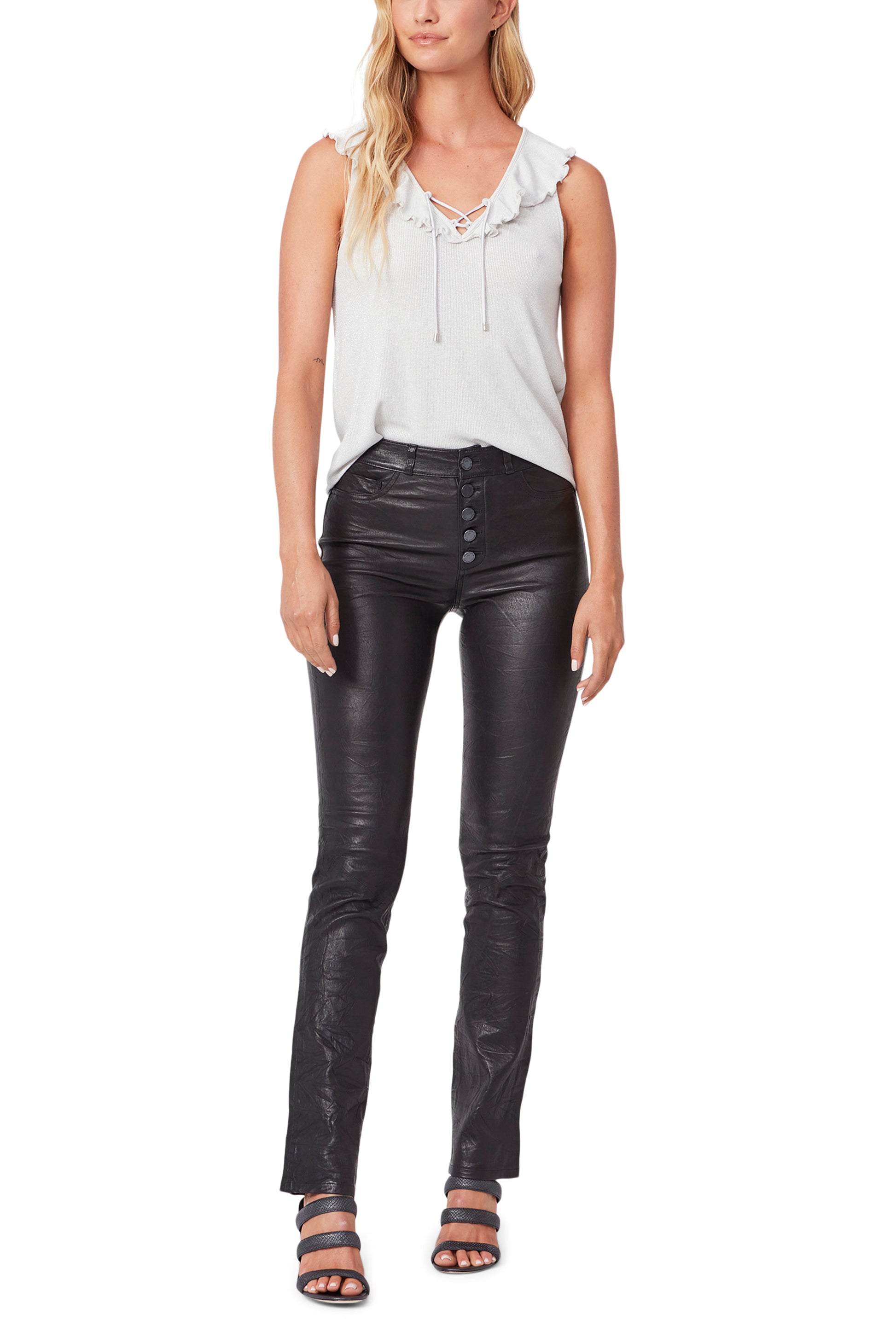 Woman wearing a white sleeveless top and black leather pants on a white background