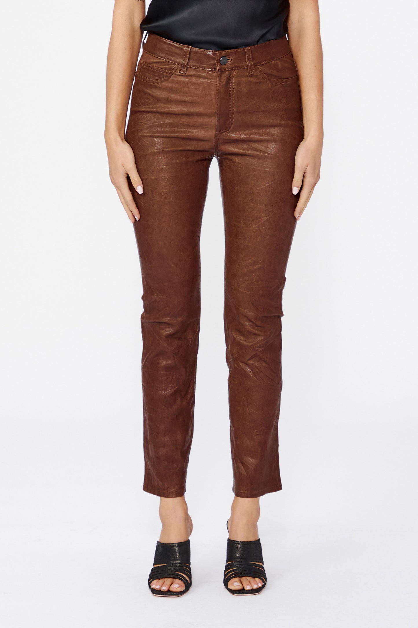 Brown leather pants worn by a person on a white background