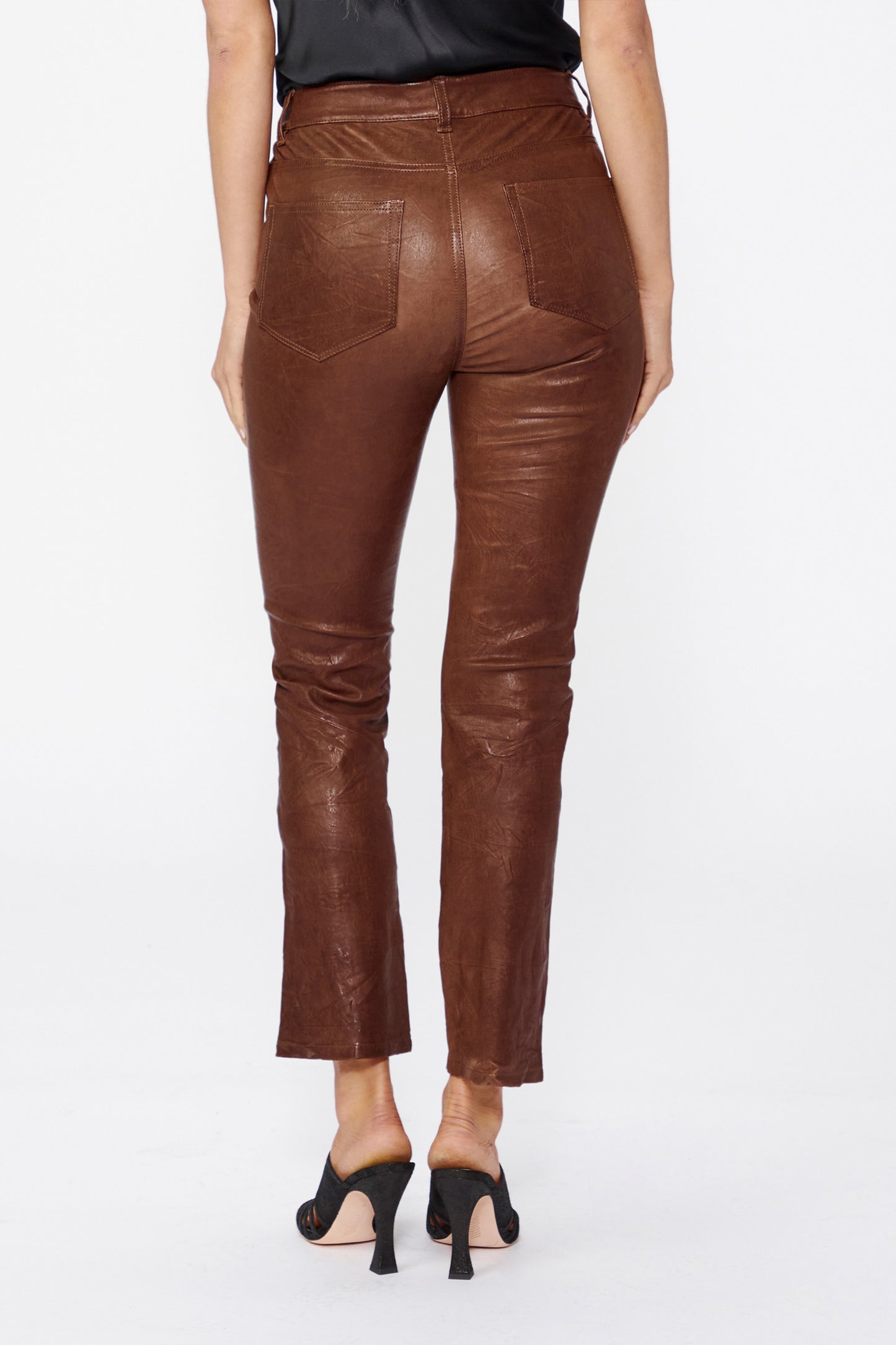 Brown leather pants worn by a person on a white background