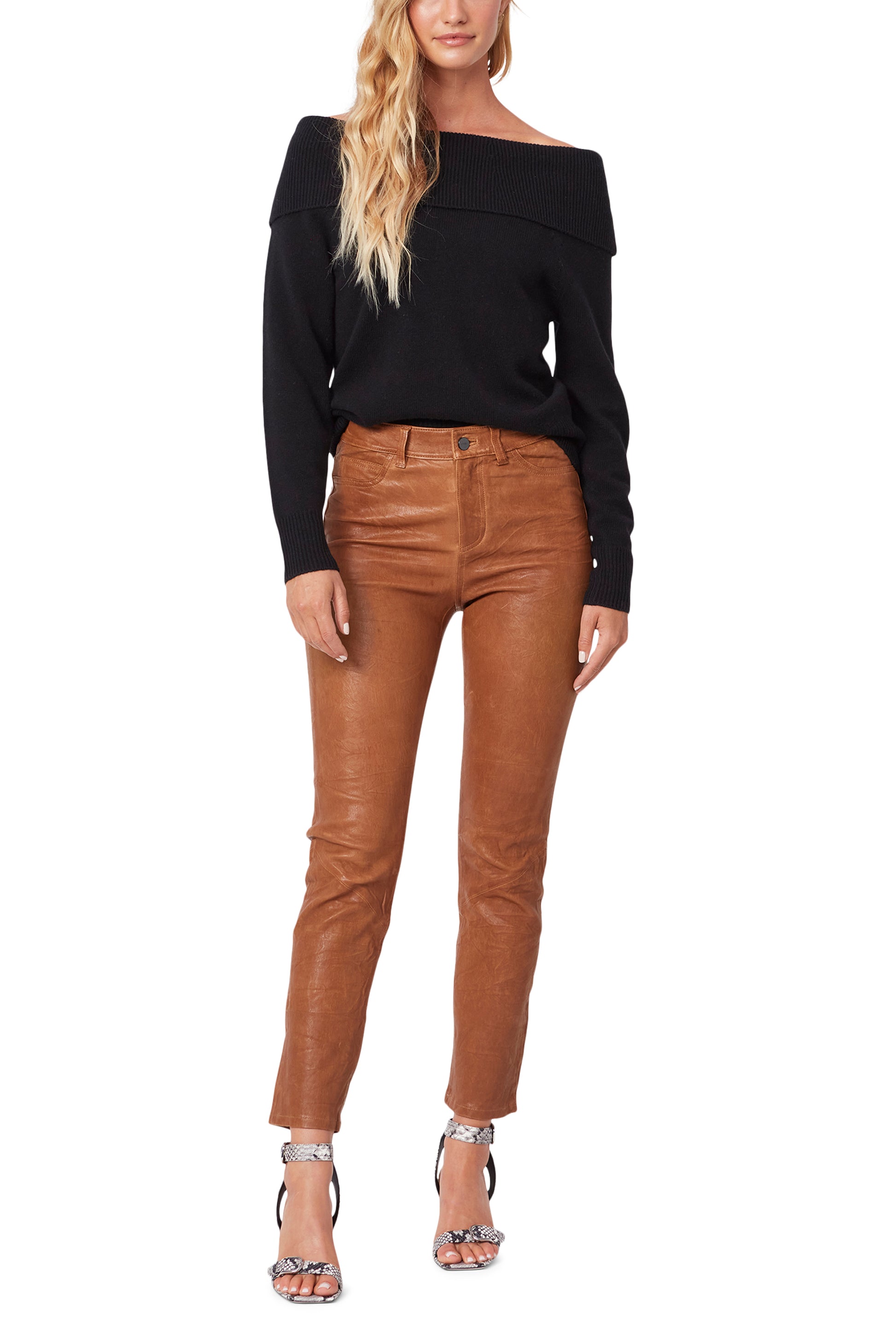 Woman wearing a black off-shoulder top and brown leather pants on a white background