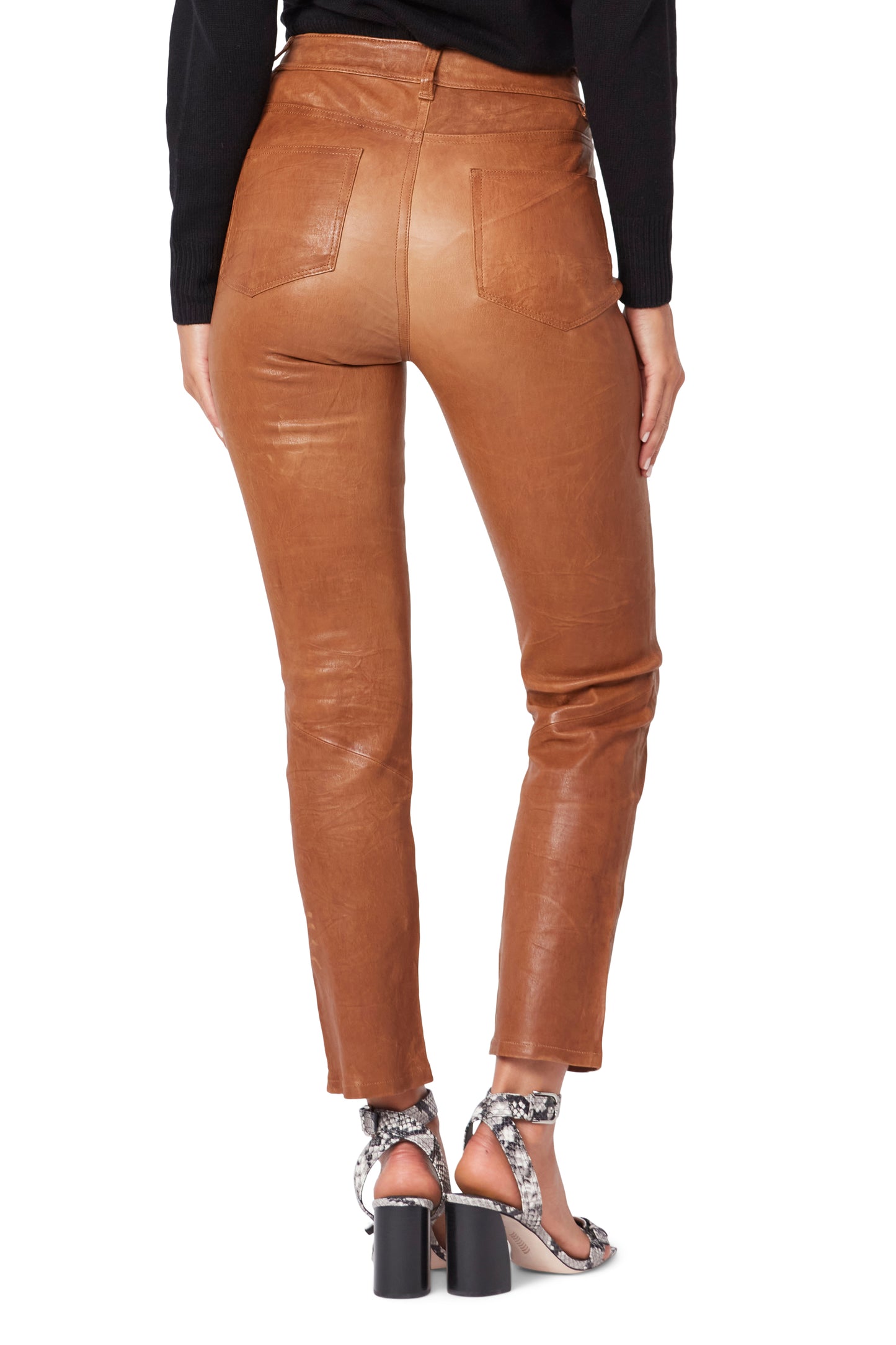 Tan leather pants worn by a person on a white background