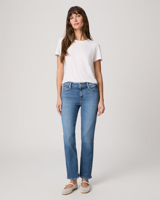 Woman wearing a white t-shirt and blue jeans on a plain background
