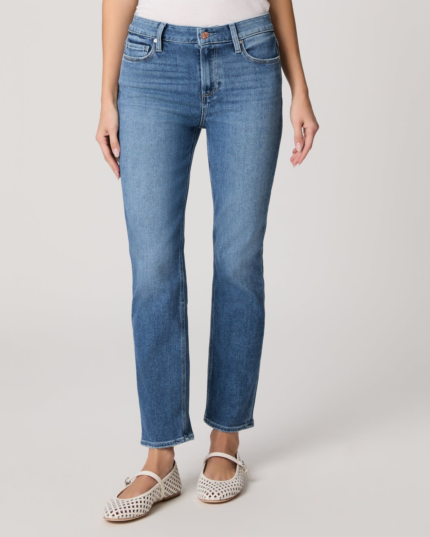 Woman wearing a white t-shirt and blue jeans on a plain background