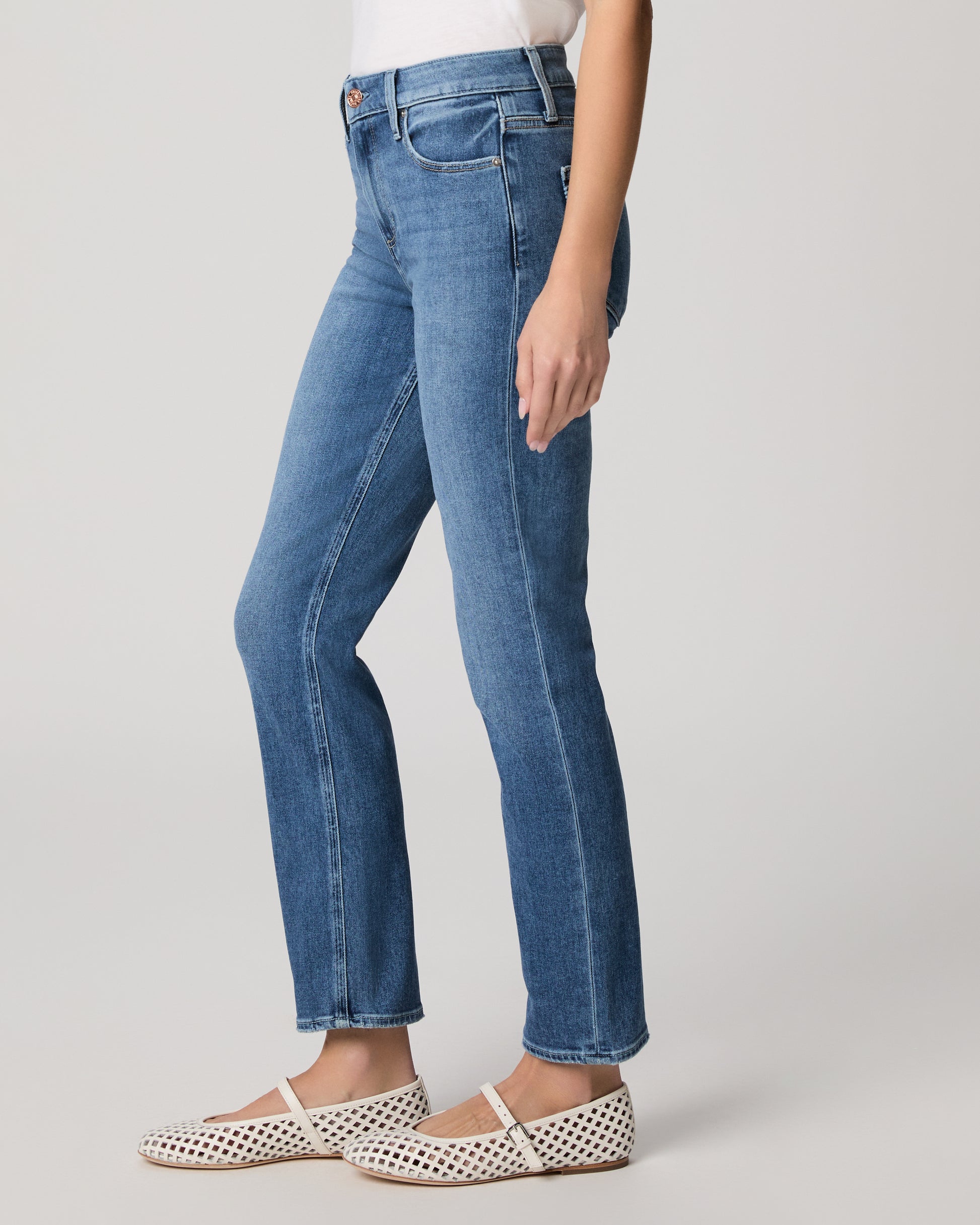 Woman wearing a white t-shirt and blue jeans on a plain background