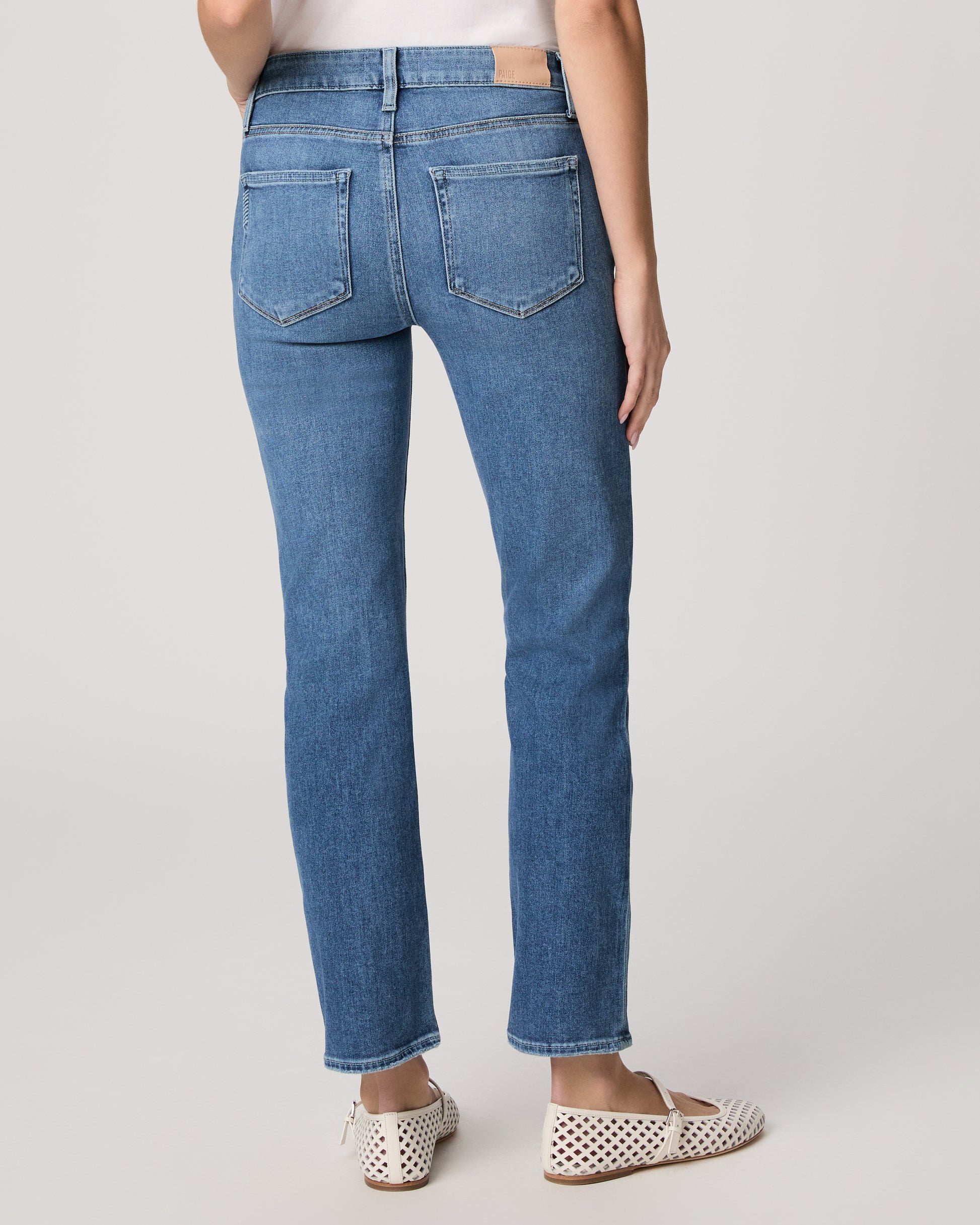 Woman wearing a white t-shirt and blue jeans on a plain background