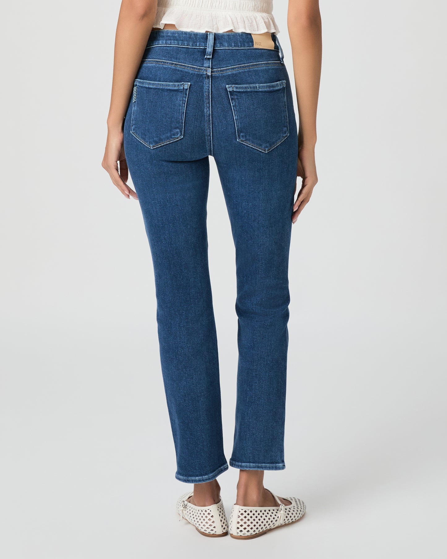 Woman wearing a white blouse and blue jeans on a white background