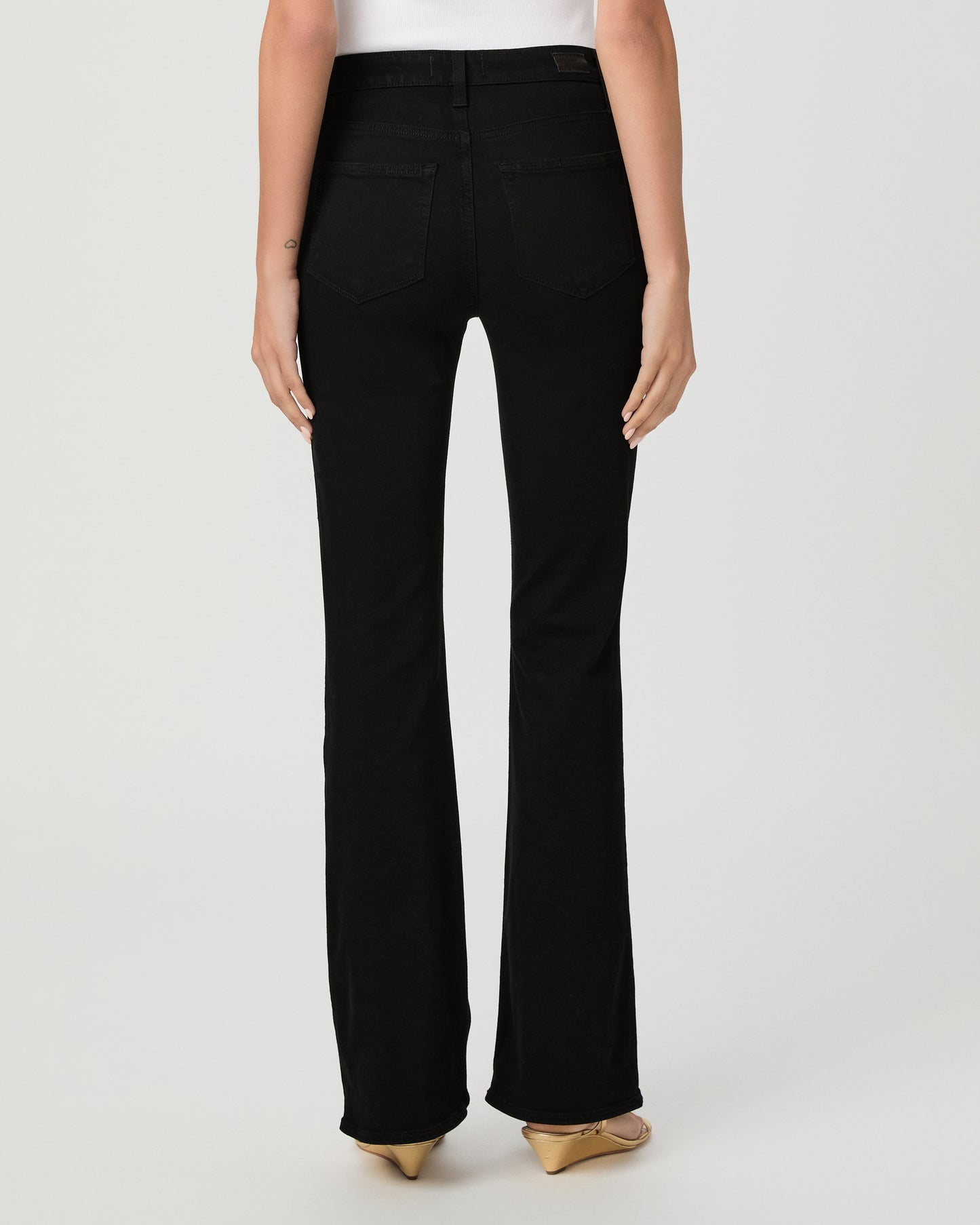 A woman modeling a light blue sheer long-sleeve blouse with ruffle trim and a button front, paired with black pants, against a plain light gray studio background.