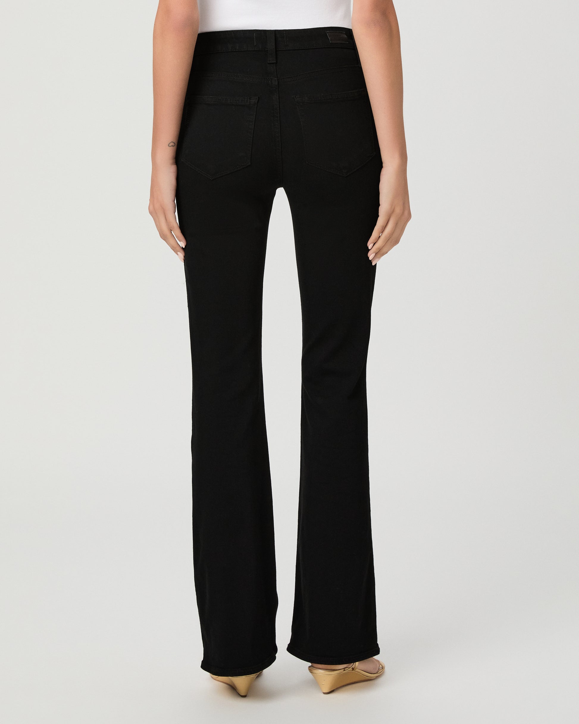 A woman modeling a light blue sheer long-sleeve blouse with ruffle trim and a button front, paired with black pants, against a plain light gray studio background.