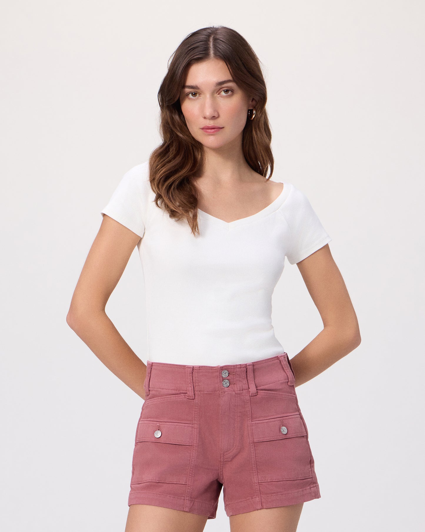 Women wearing a white tee and pink shorts paired with white sandals on a white background