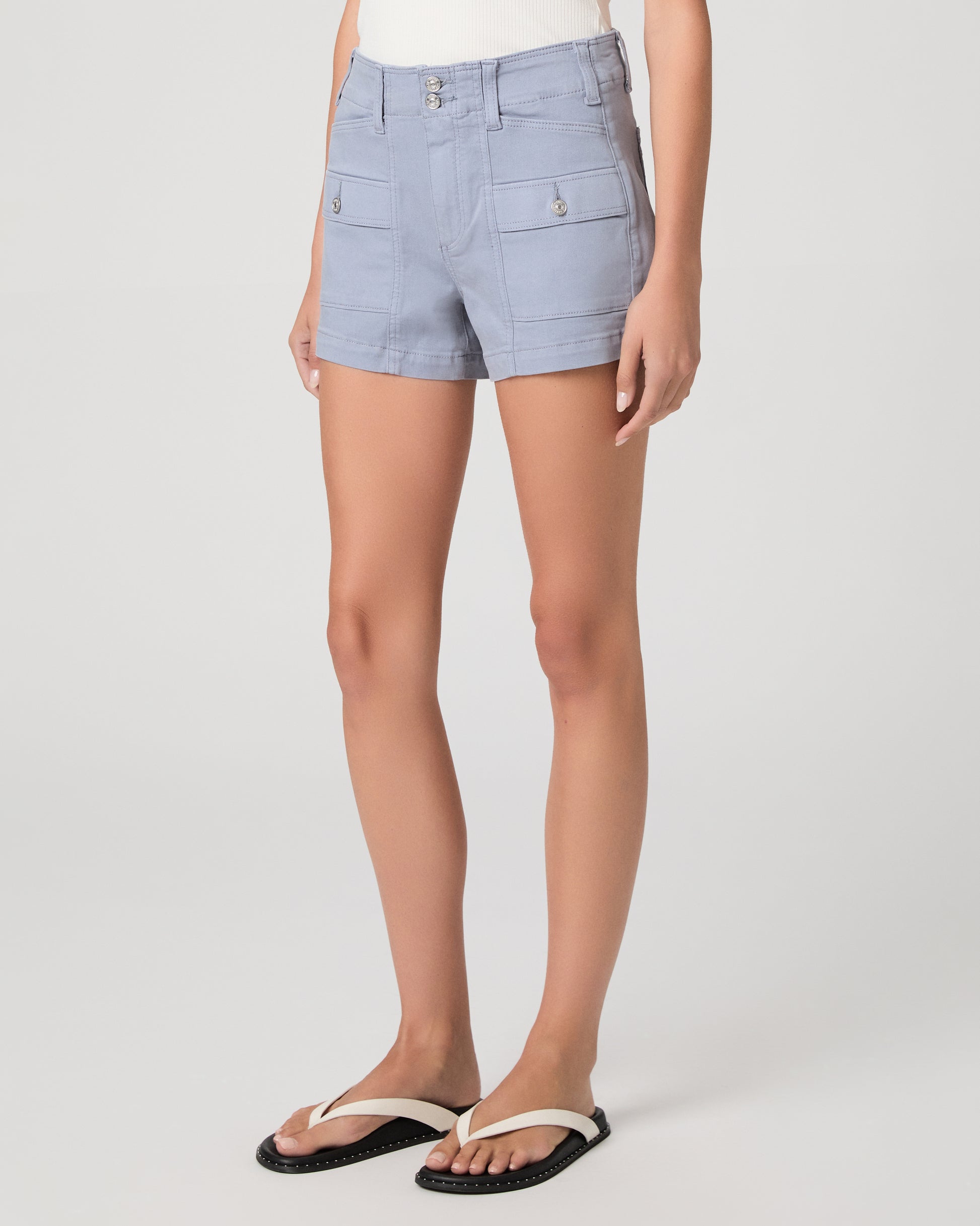 Woman wearing a white sleeveless top and light blue shorts on a white background