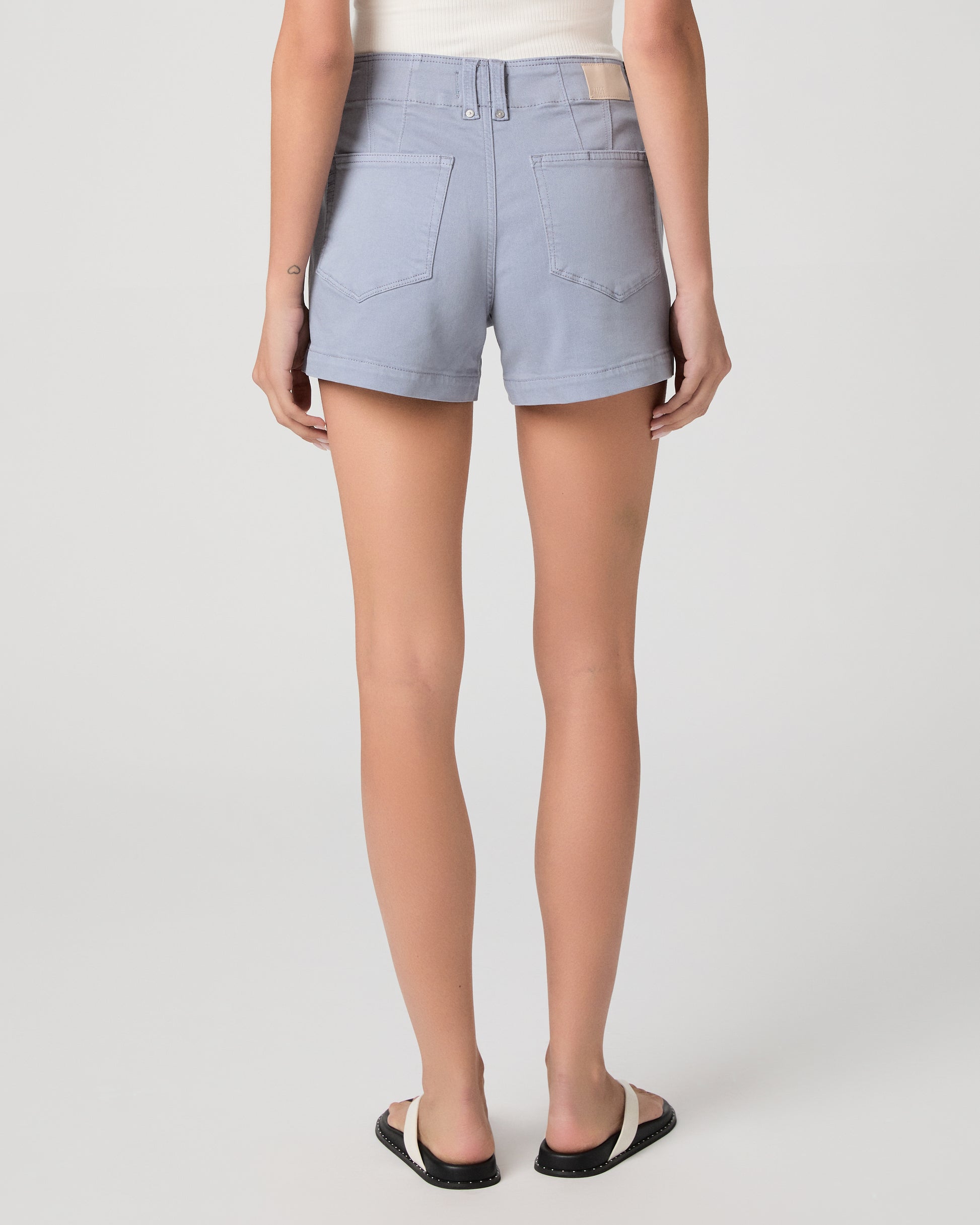 Woman wearing a white sleeveless top and light blue shorts on a white background