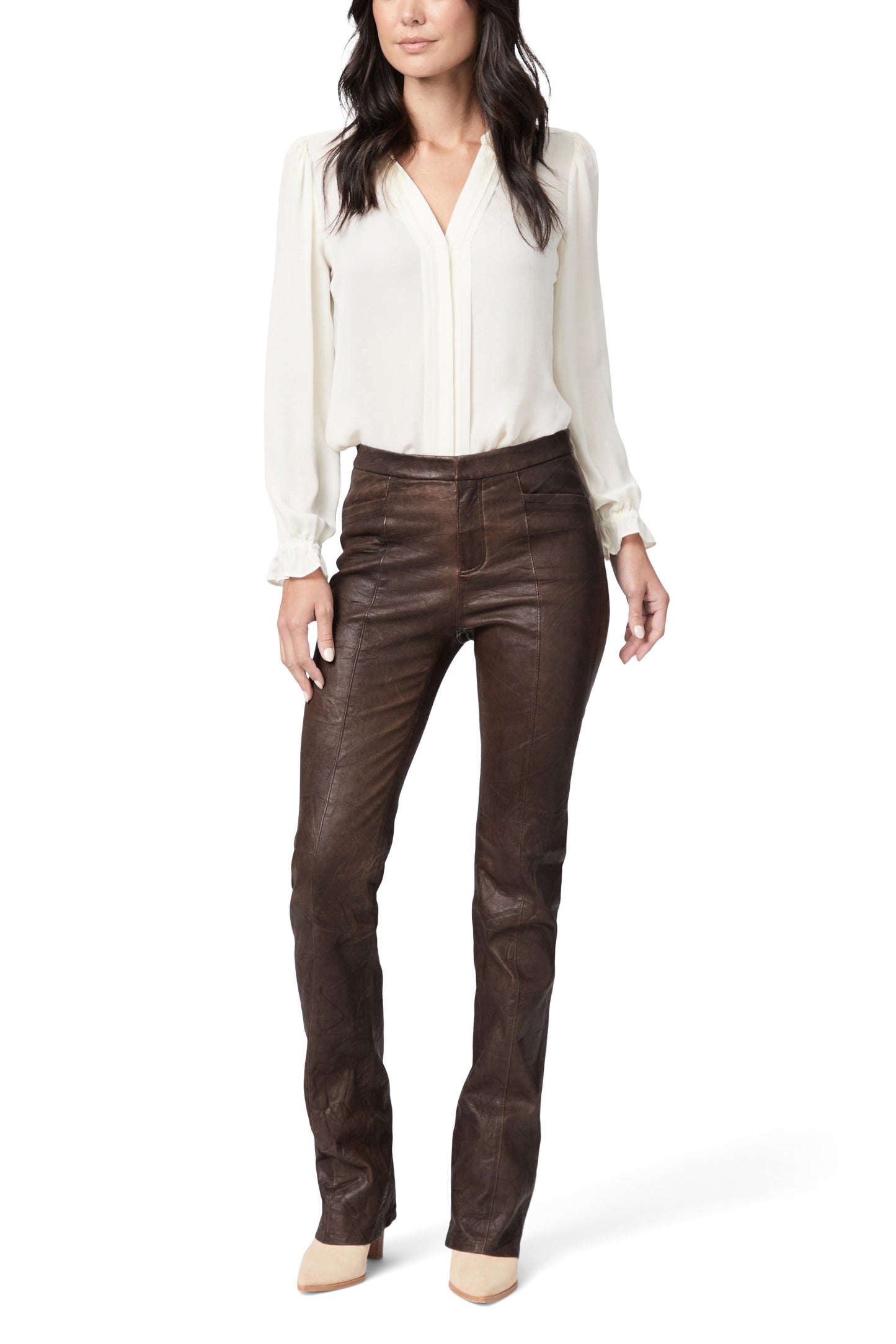 Woman wearing a white blouse and brown leather pants on a white background