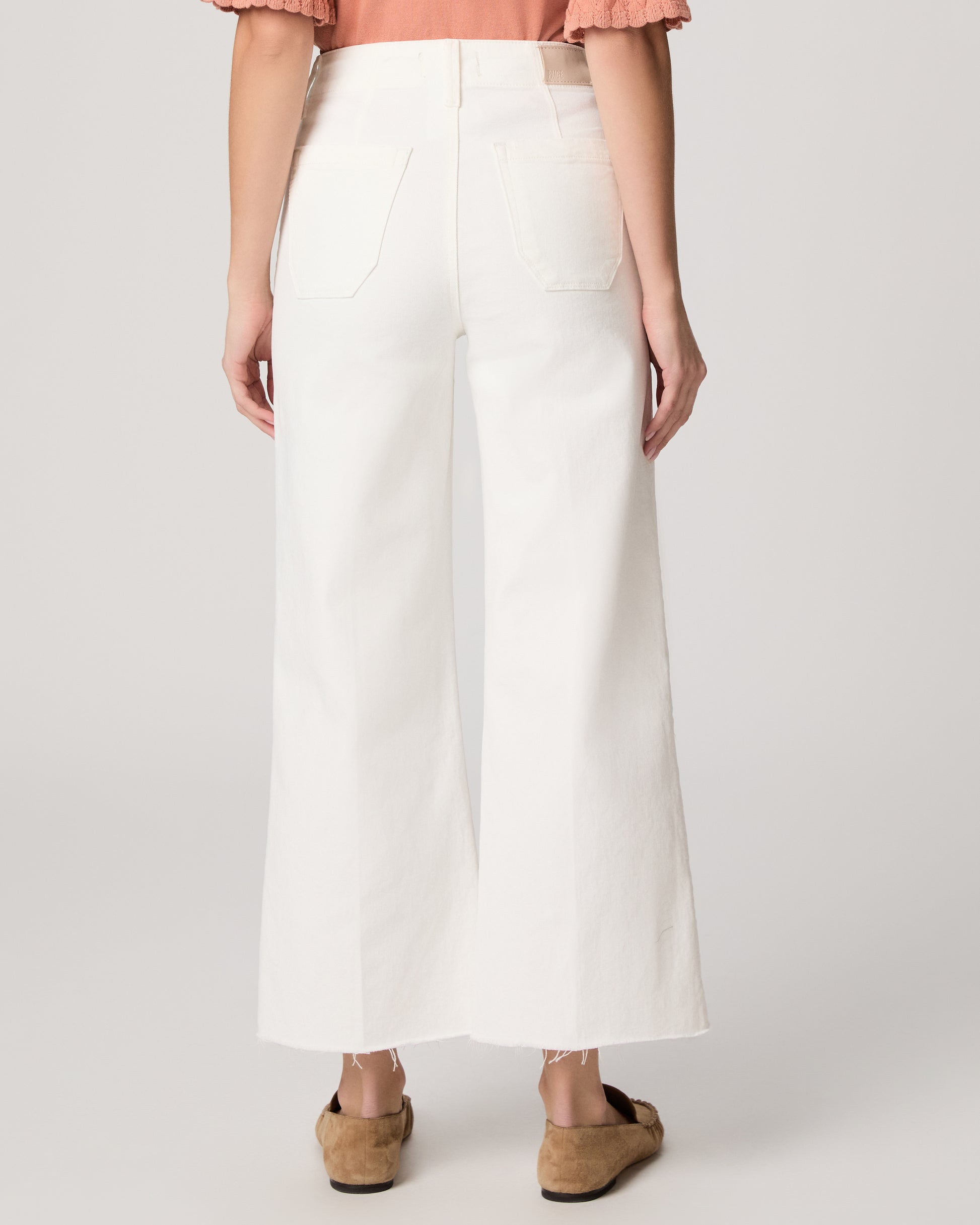 Person wearing a white wide-leg pants with a plain background