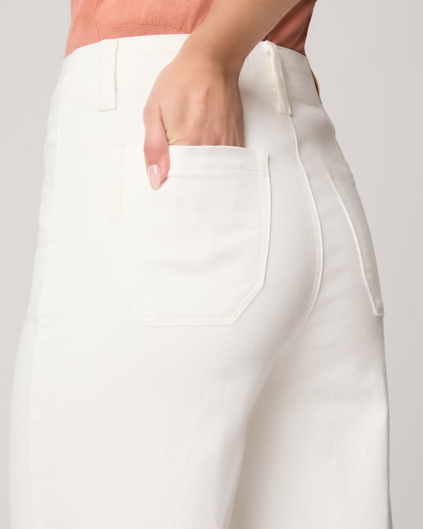 Close-up of a person wearing white pants with a plain background