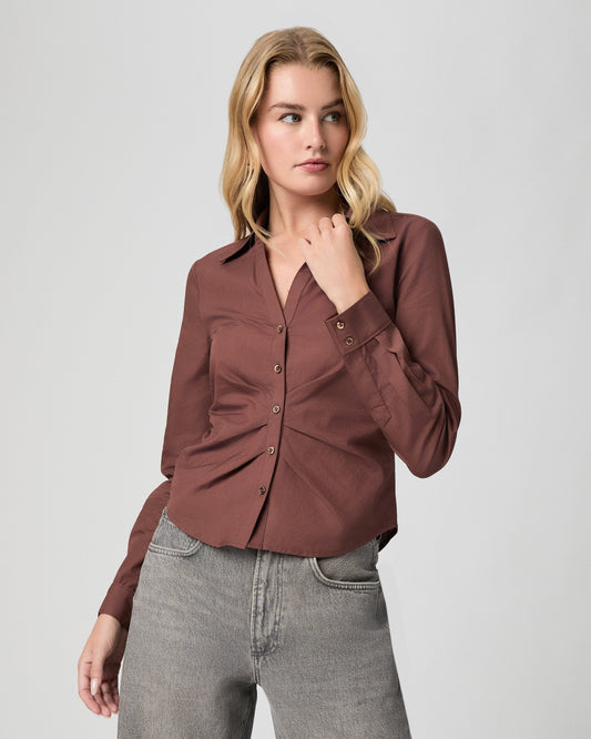 Alera Shirt in French Press brown; close-up of model from the thighs up, one hand at the collar, worn with grey jeans