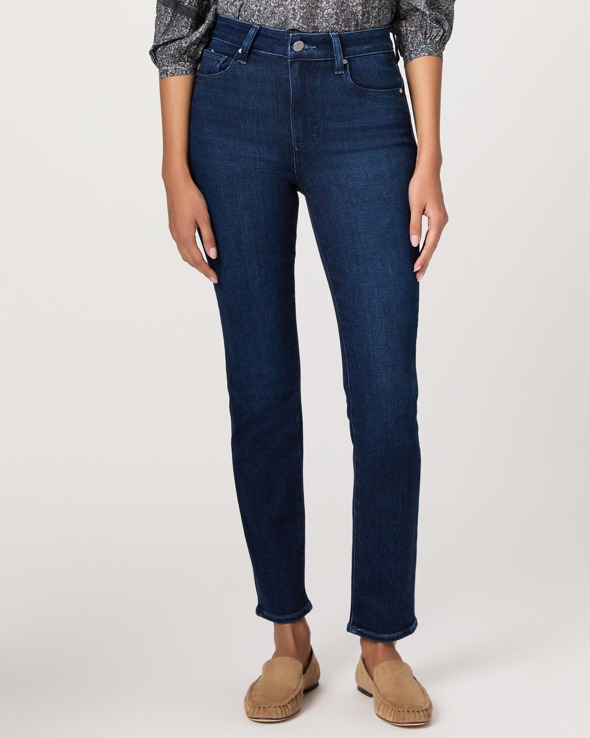 Woman wearing a blue patterned blouse and blue jeans on a white background