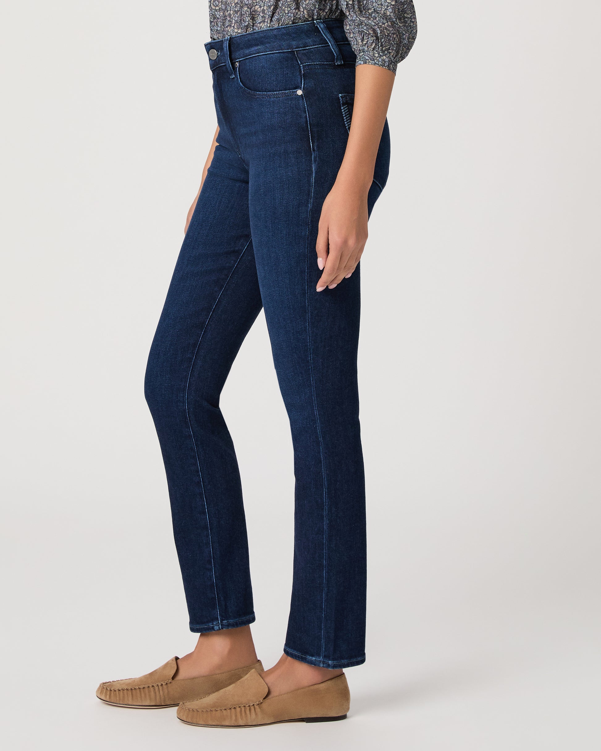 Woman wearing a blue patterned blouse and blue jeans on a white background