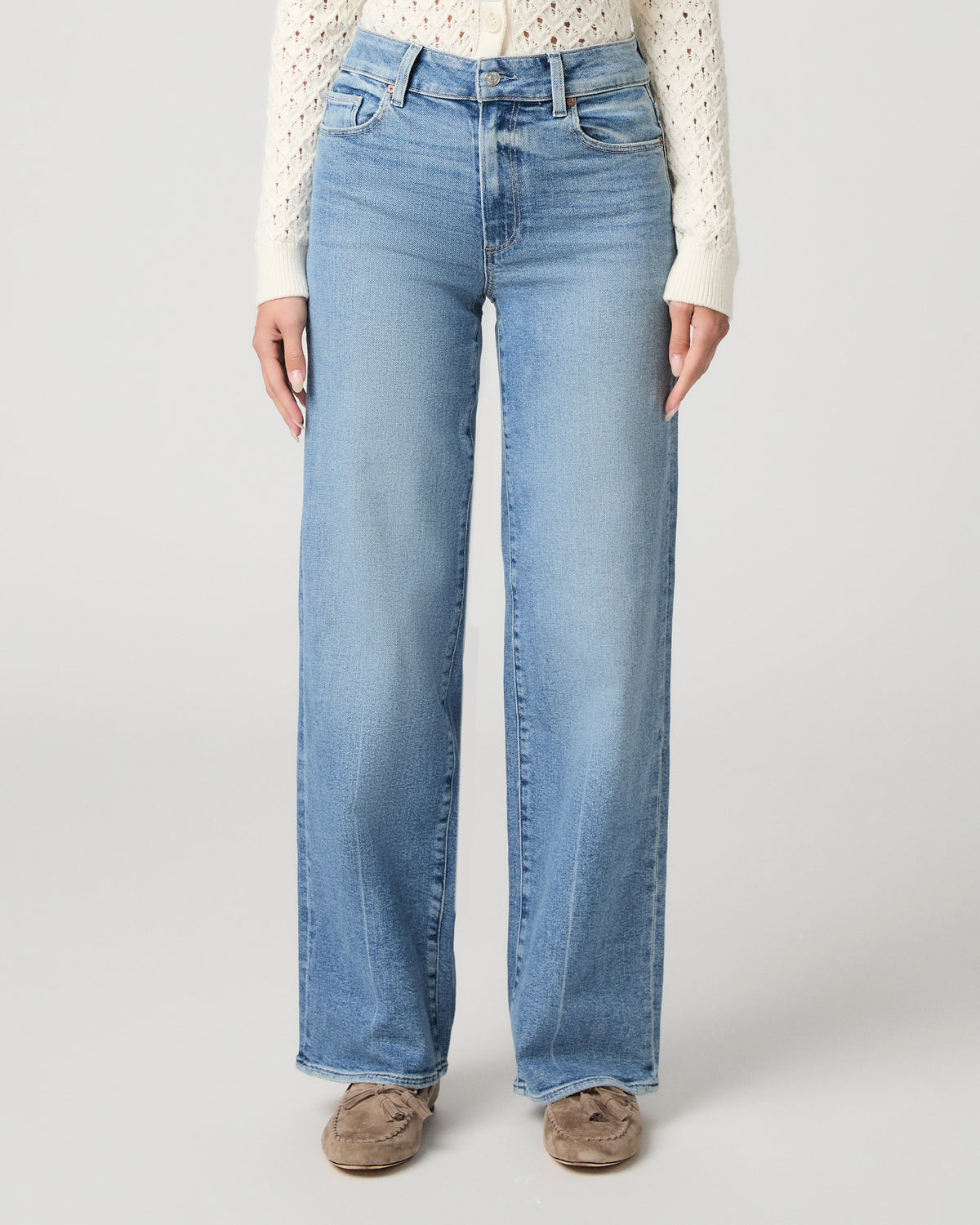 Woman in a white top with light blue jeans and a white background