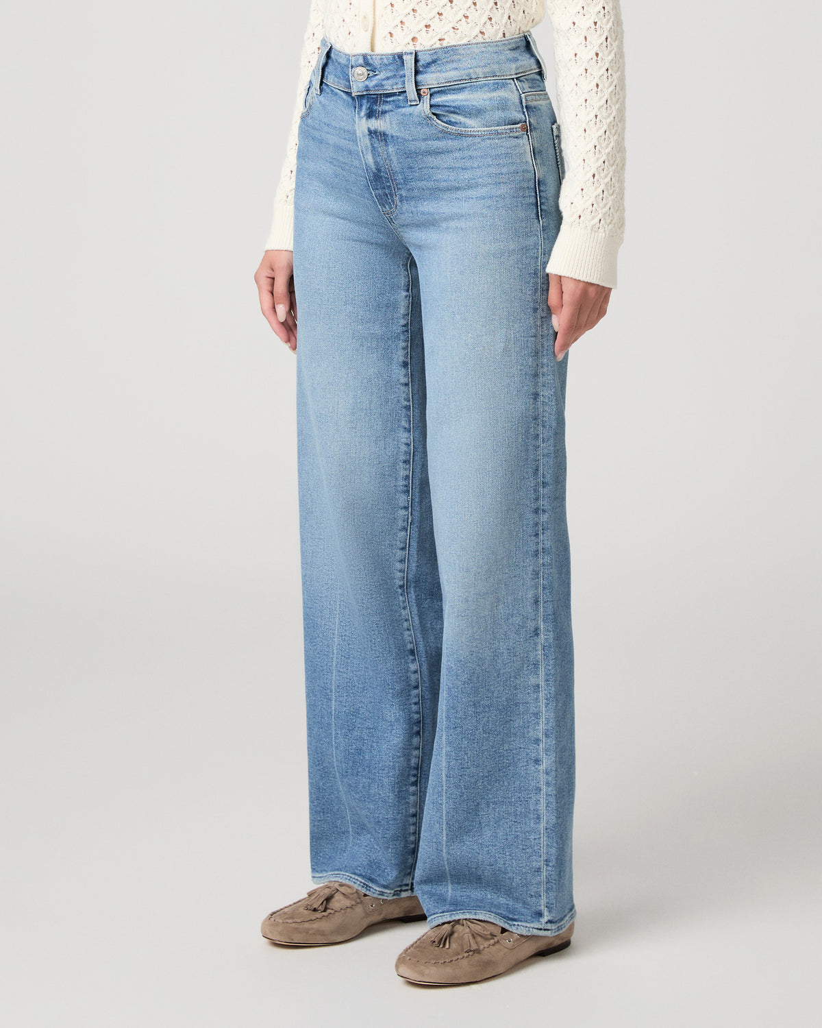 Woman in a white top with light blue jeans and a white background
