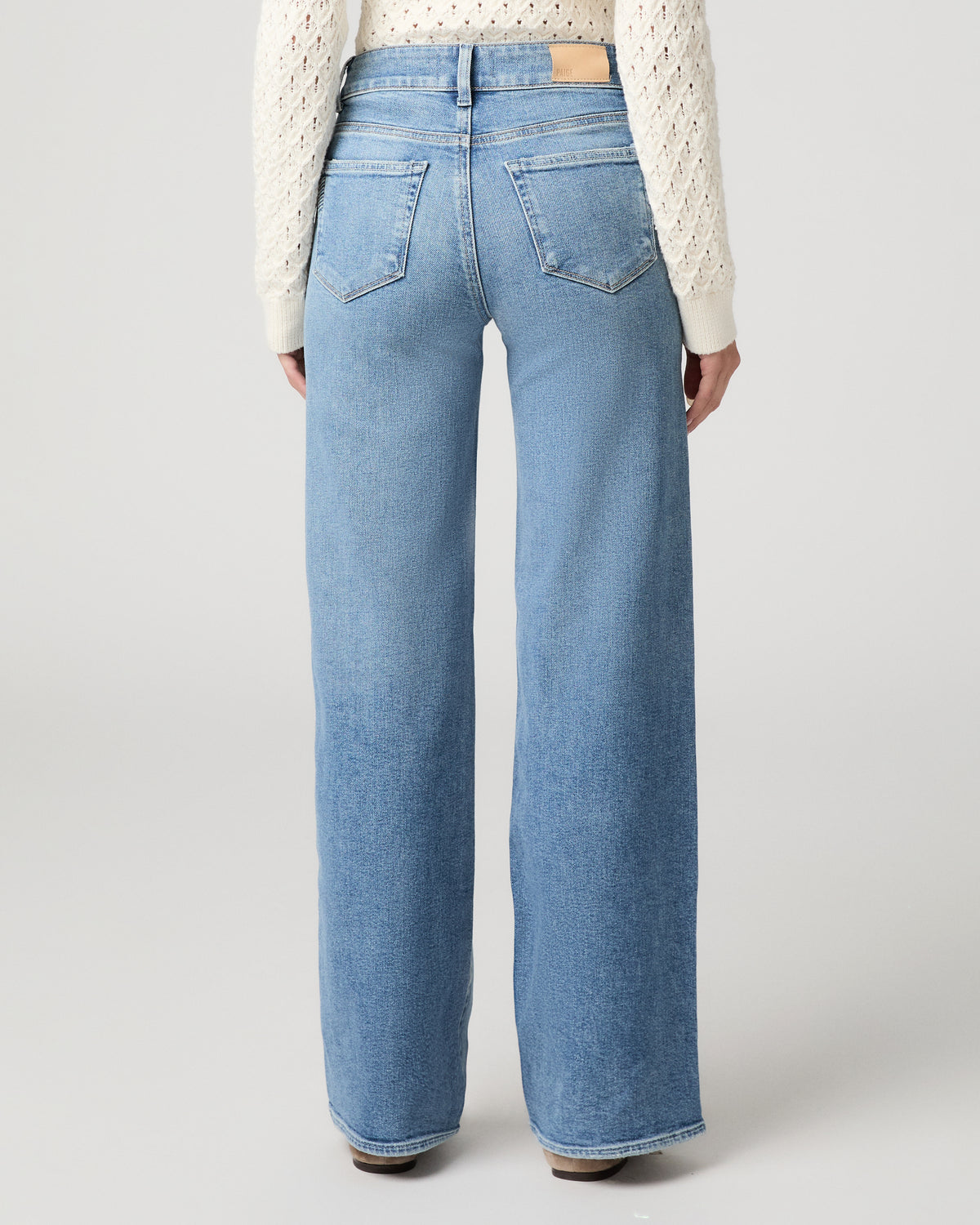 Woman in a white top with light blue jeans and a white background