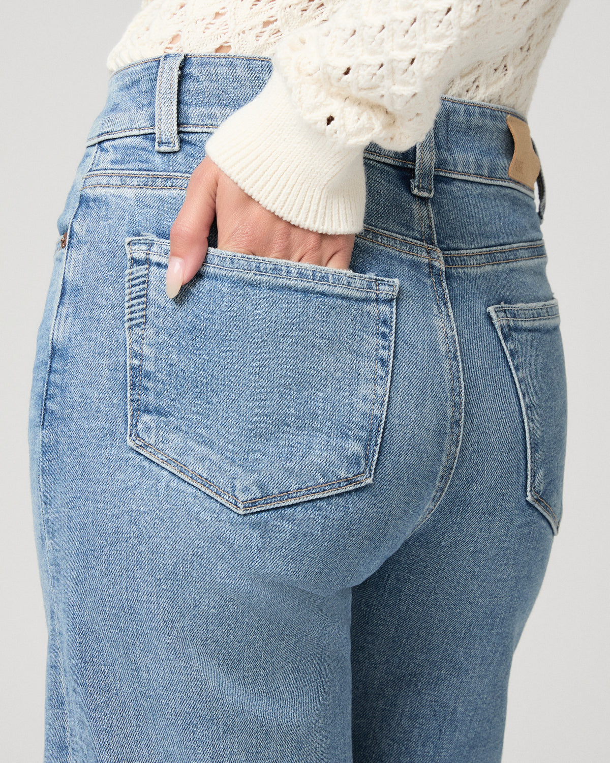 Woman in a white top with light blue jeans and a white background