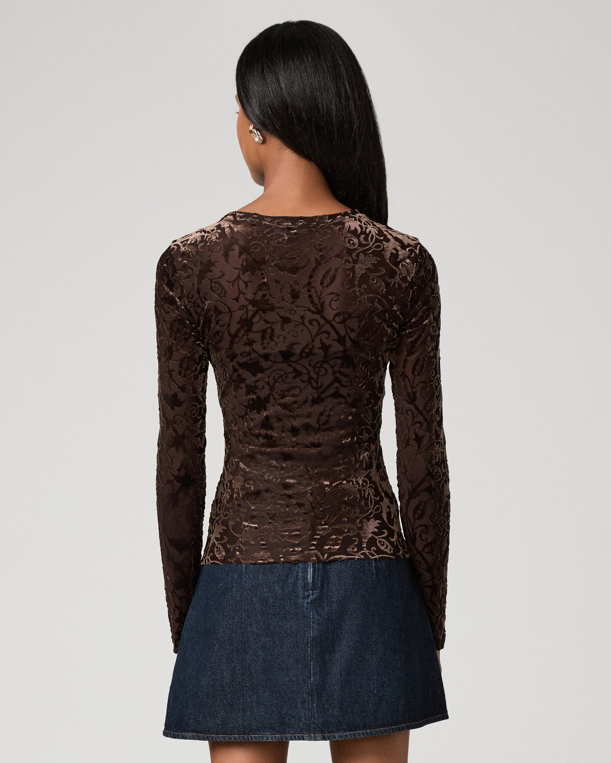 Back view close-up of a woman wearing a brown velvet burnout long-sleeve top with a floral pattern.