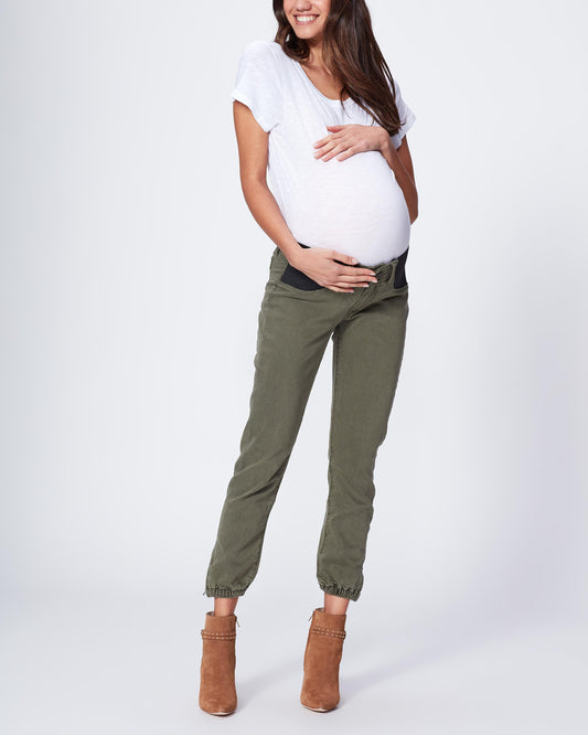 Pregnant woman wearing green pants and a white top on a white background