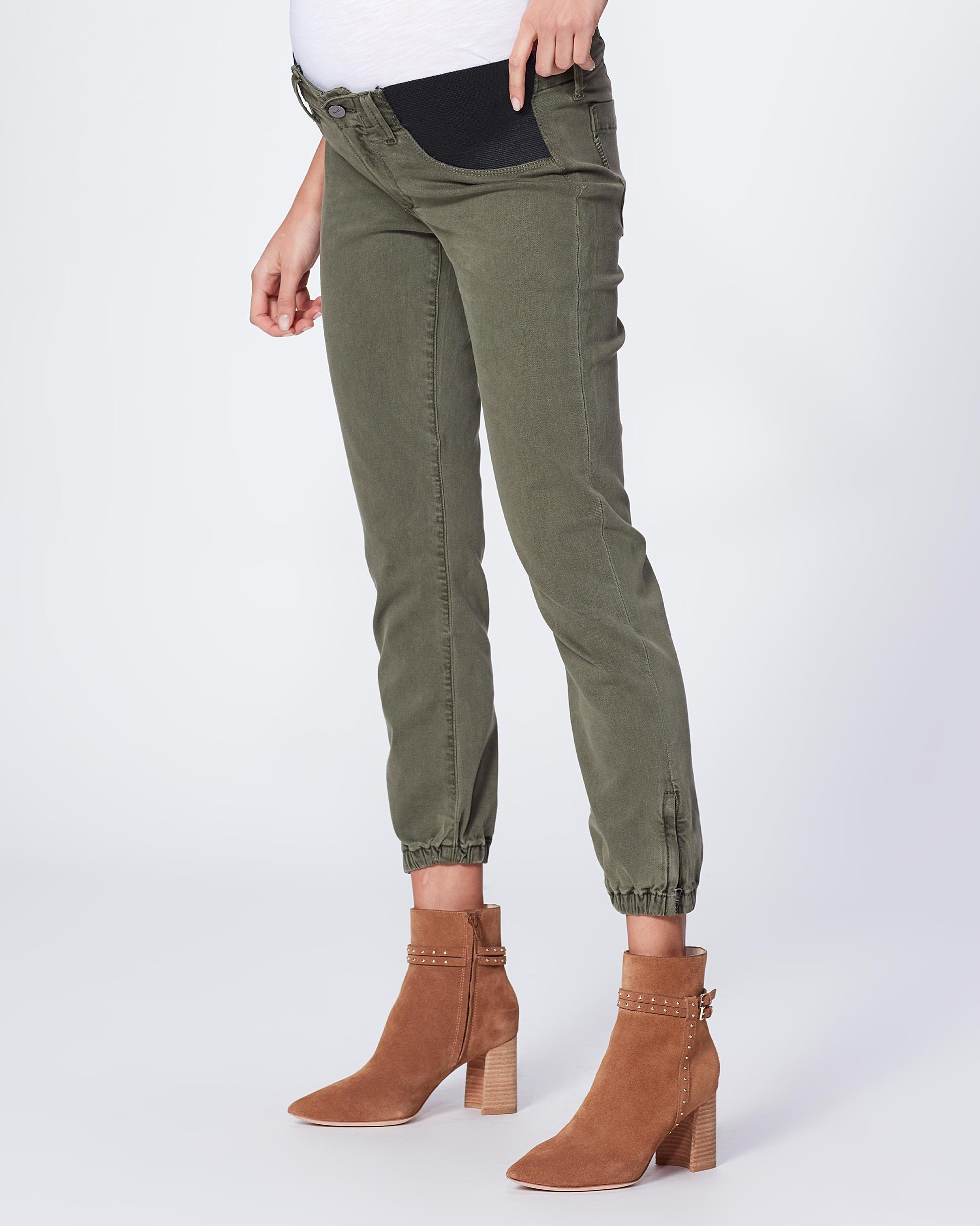 Person wearing green pants and brown boots on a white background