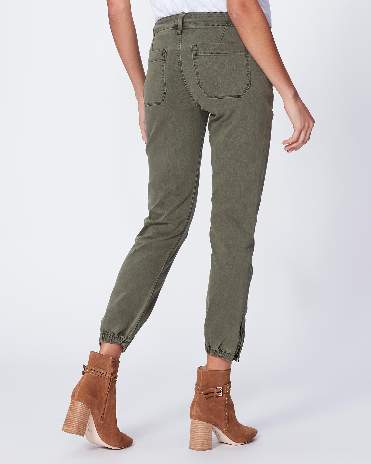 Person wearing olive green pants and brown boots on a white background