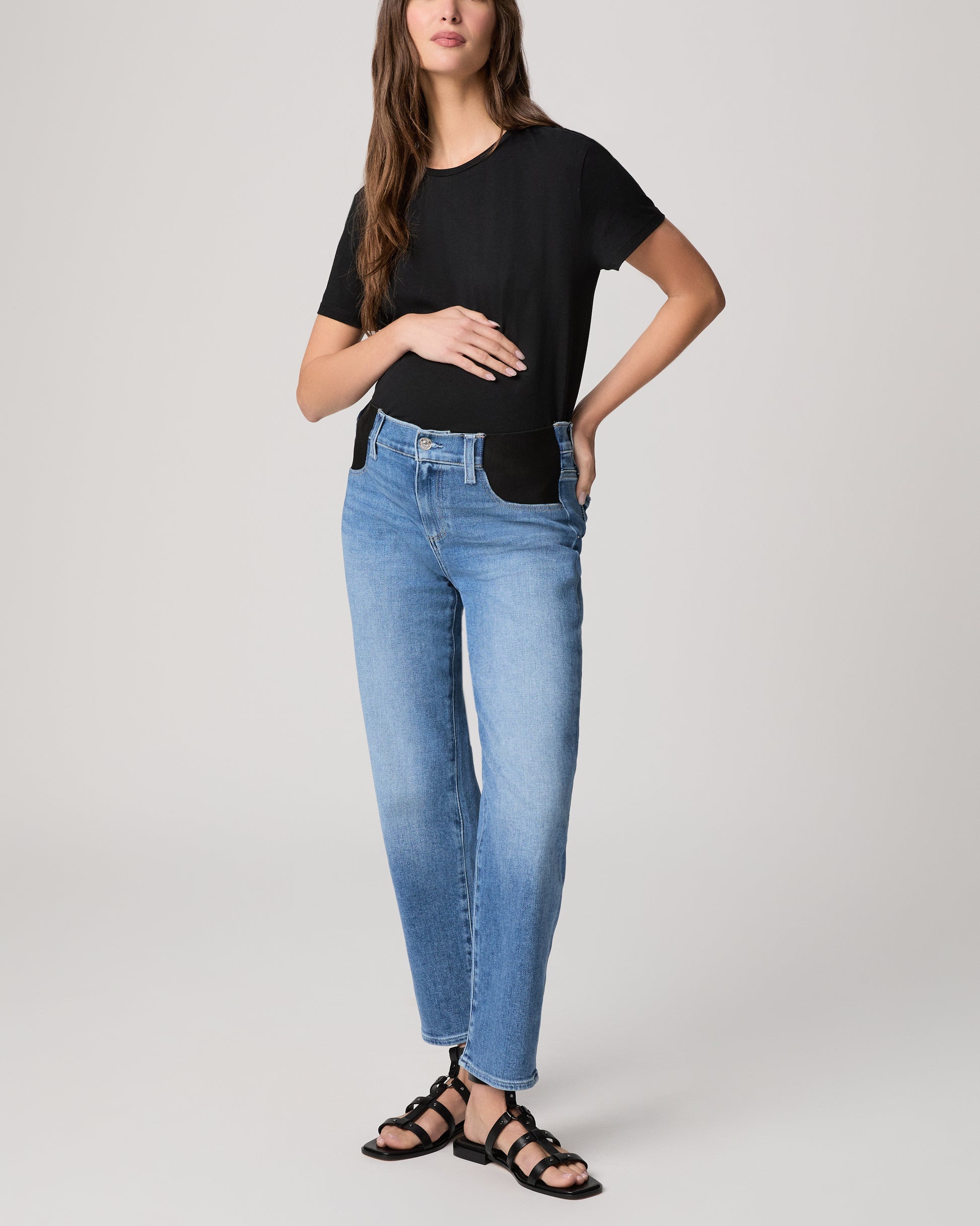 Woman wearing a black t-shirt and blue jeans on a plain background