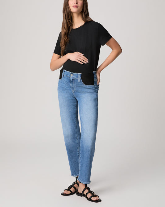 Woman wearing a black t-shirt and blue jeans on a plain background