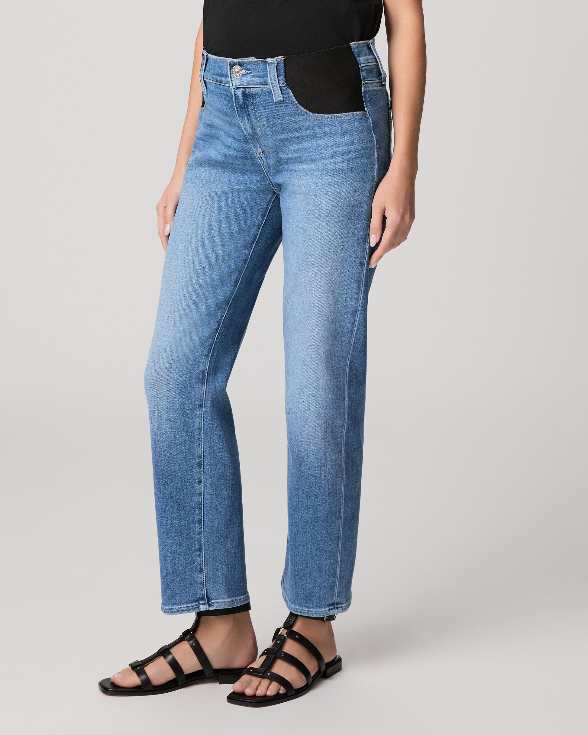 Woman wearing a black t-shirt and blue jeans on a plain background