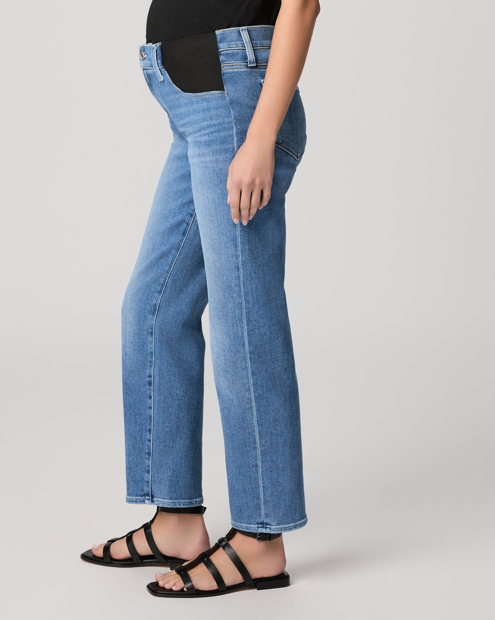 Woman wearing a black t-shirt and blue jeans on a plain background