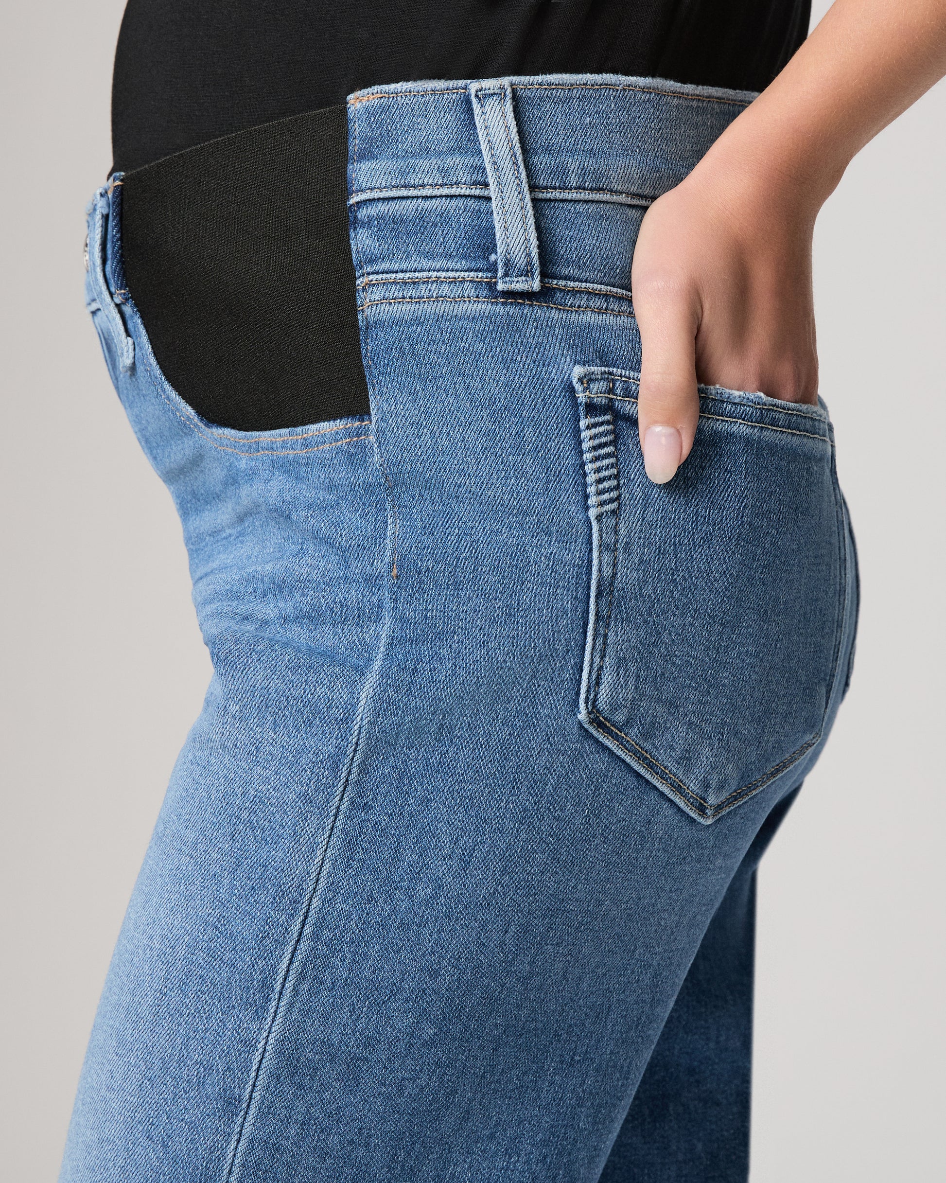 Woman wearing a black t-shirt and blue jeans on a plain background
