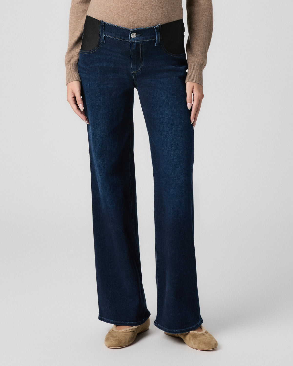 Front view from the waist down of pregnant model with arms at her sides, showing the black stretch side panels of Anessa Maternity Jeans in Amagansett dark wash and tan flats
