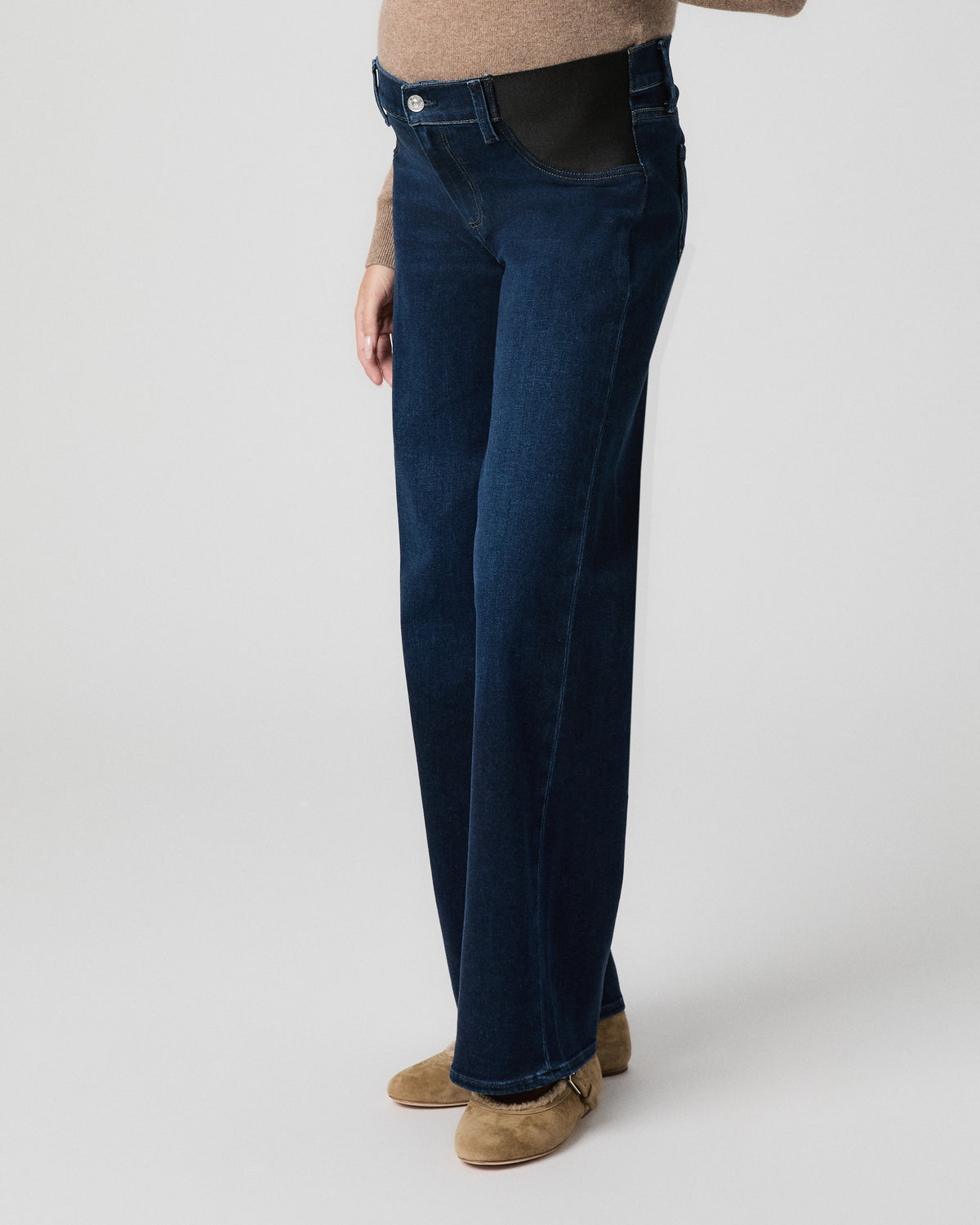 Side view from the waist down of model showing the black stretch side panel and wide leg of Anessa Maternity Jeans in Amagansett dark wash with tan flats