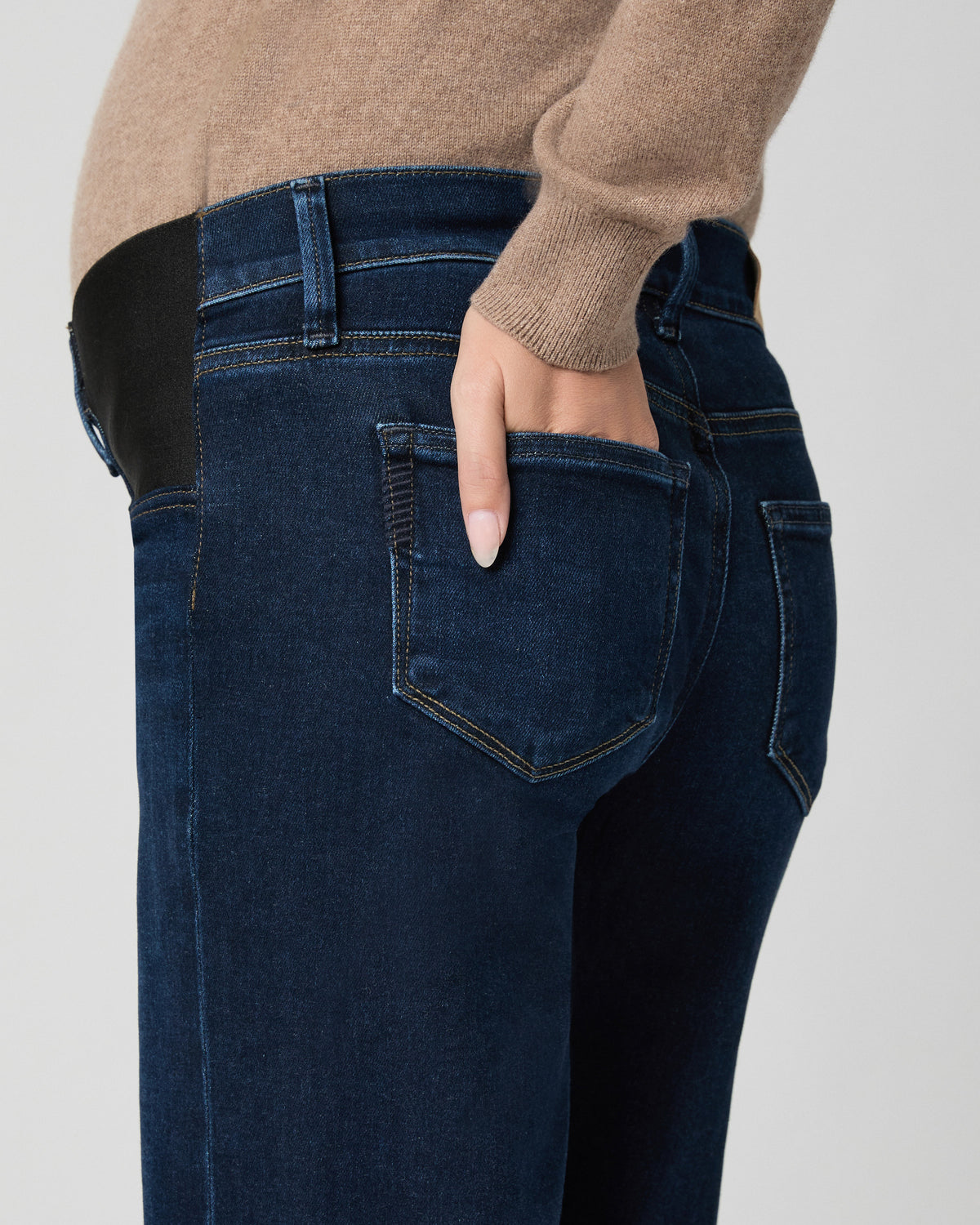 Side-angle close-up of the back pocket and black stretch side panel of Anessa Maternity Jeans in Amagansett, model's hand tucked into the pocket