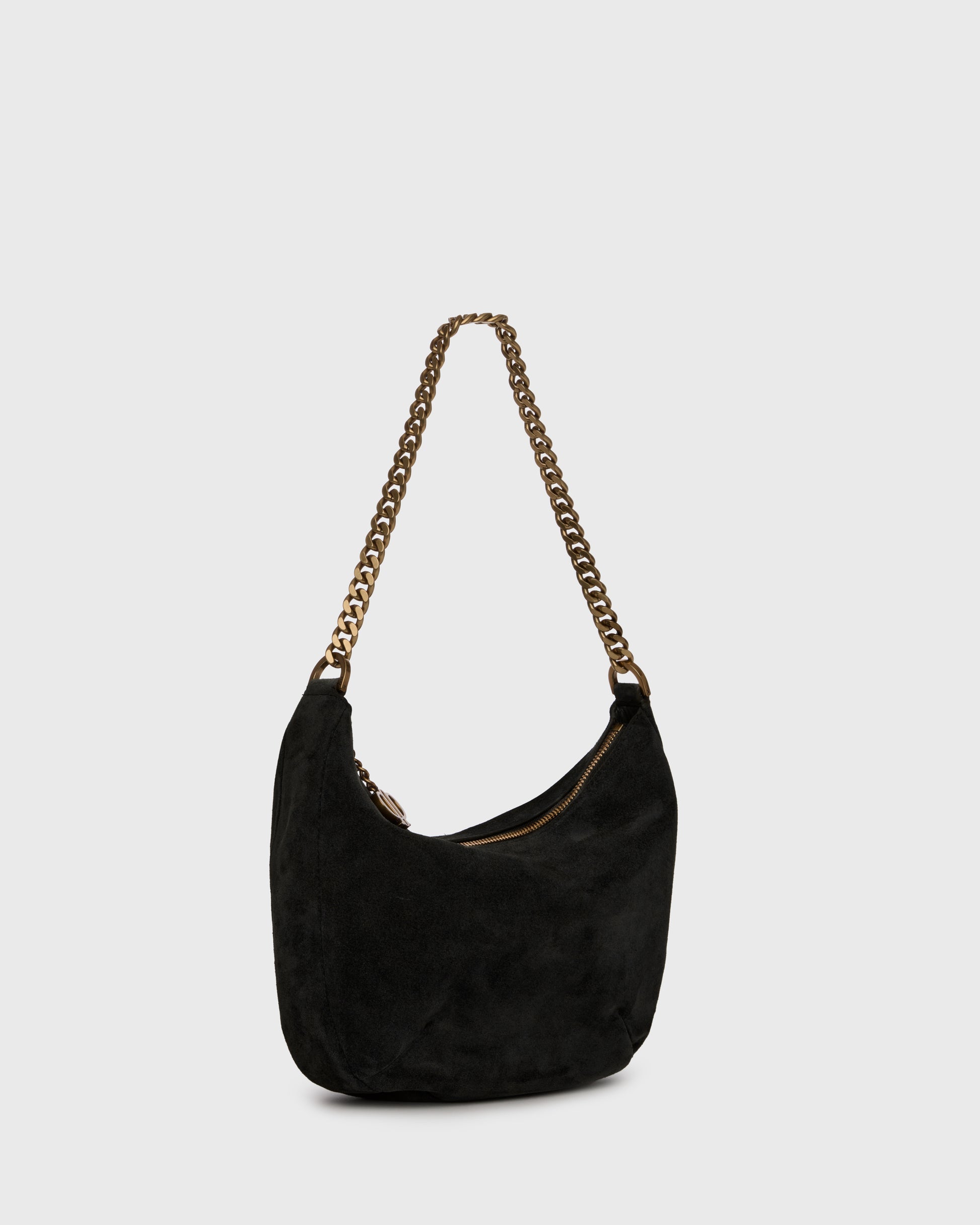 A black suede crescent-shaped shoulder bag with a gold-tone chain strap and a small gold logo charm, set against a plain light gray background.