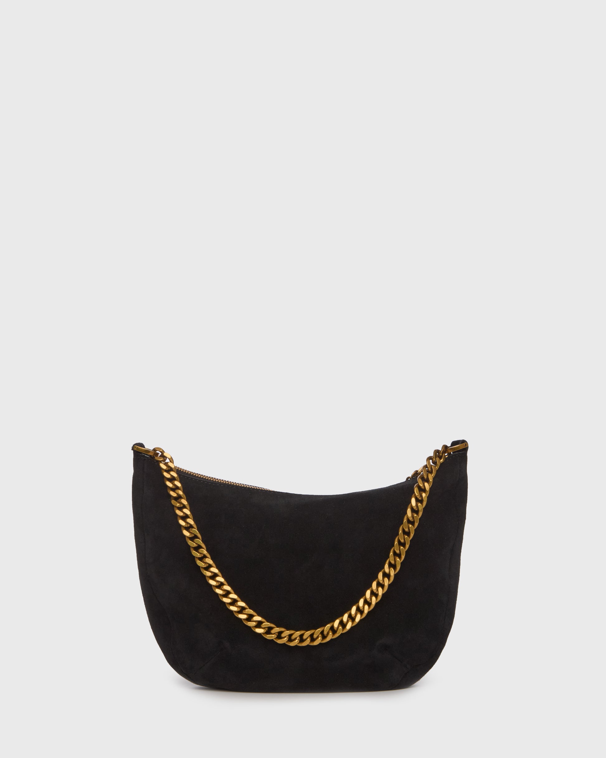 A black suede crescent-shaped shoulder bag with a gold-tone chain strap and a small gold logo charm, set against a plain light gray background.