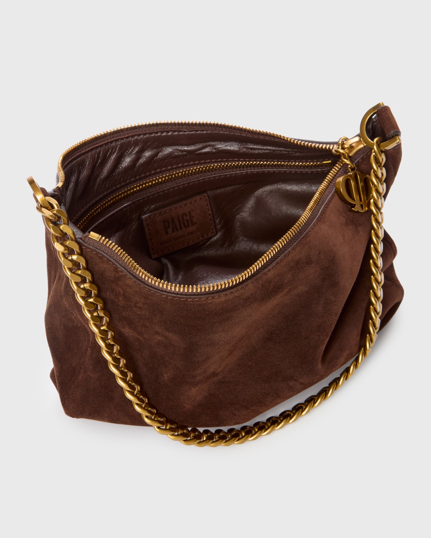 A brown suede shoulder bag with a gold chain strap and gold zipper, shown open to reveal a dark brown leather interior with a 'PAIGL' brand patch.