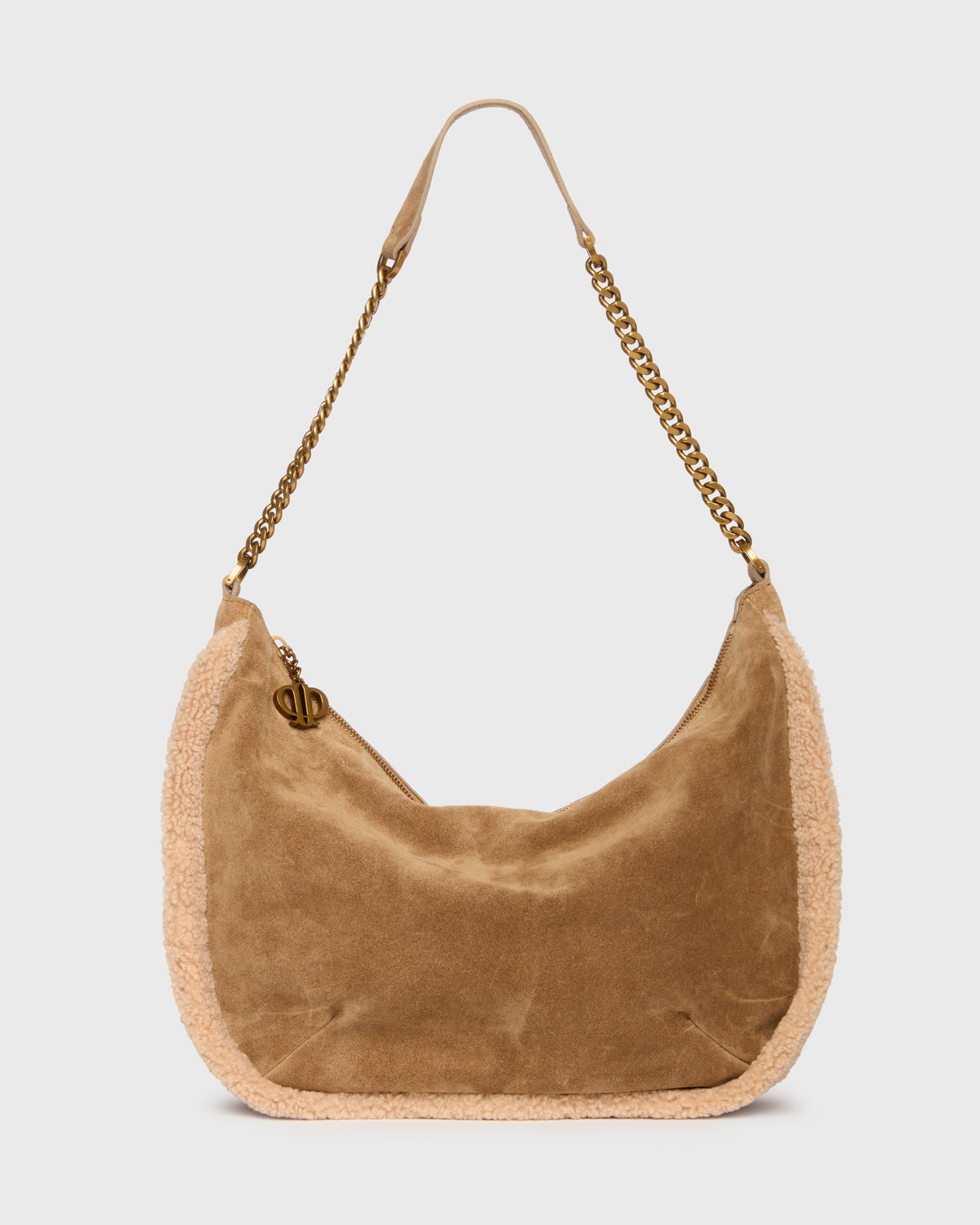 A tan suede crescent-shaped shoulder bag with a beige textured trim and a gold-tone chain strap, shown against a light gray background.