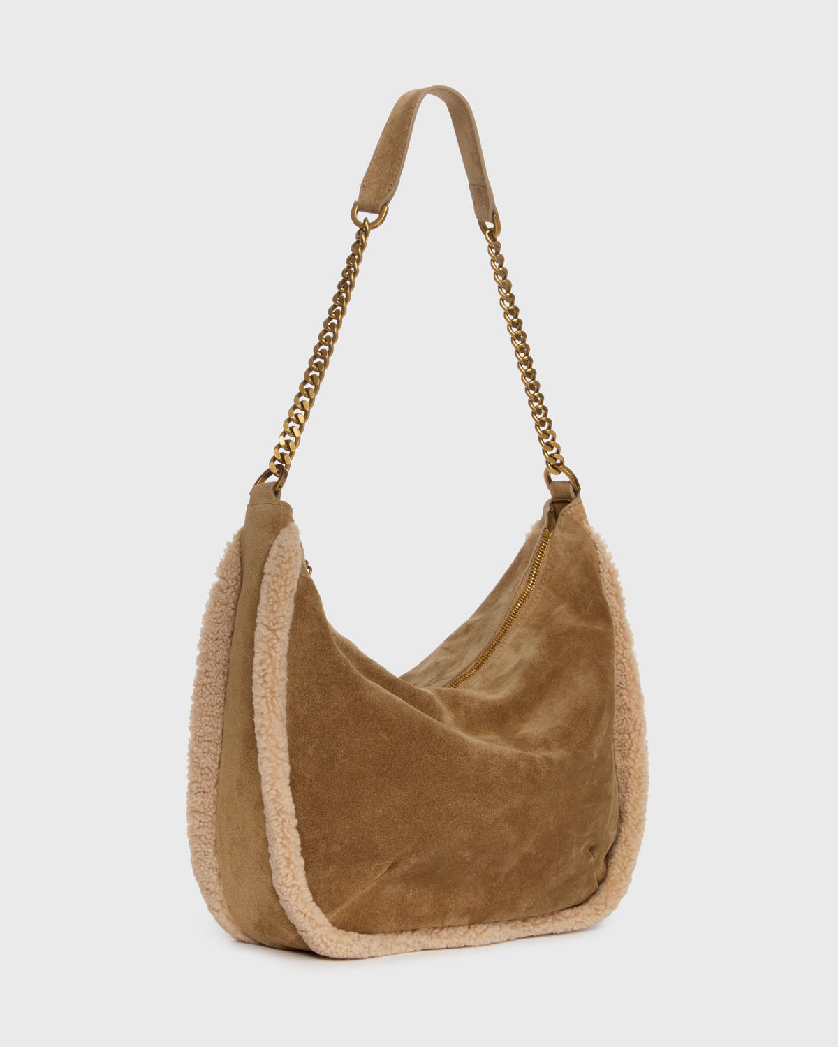 A tan suede crescent shoulder bag with a beige sherpa lining and a gold-tone chain strap, shown against a light gray background.