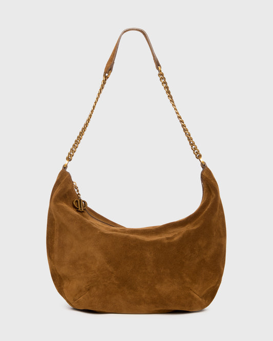 A brown suede crescent-shaped shoulder bag with a gold-tone chain strap and a small gold-tone logo clasp, shown against a light gray background.